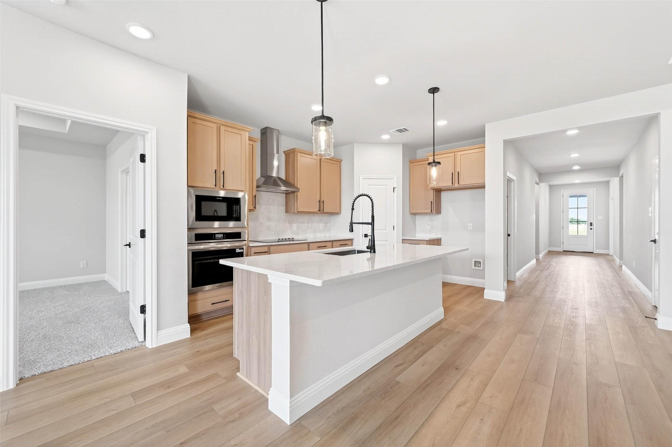 Modern kitchen with large island and stainless appliances in The Holly C floor plan at Parks at Foster Crossing, Anna, TX.
