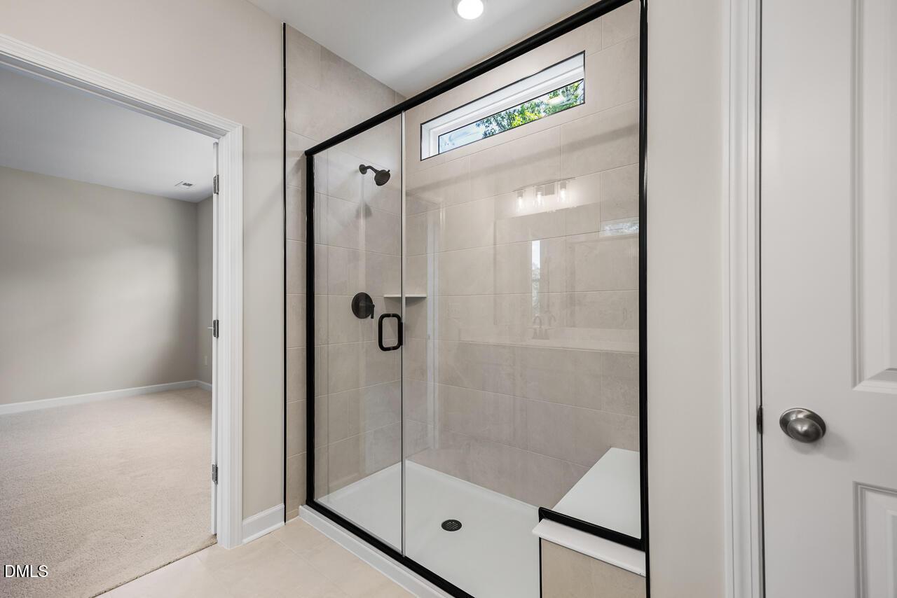 Modern walk-in shower with black frame, glass door, and tiled walls in The Chestnut floor plan, Montrose, Aberdeen, NC.