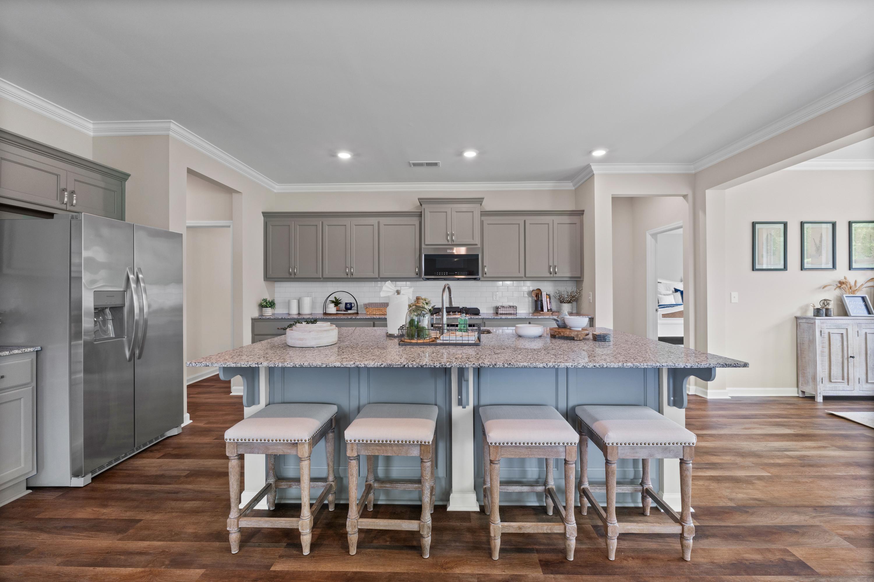 Spacious modern kitchen at Riverton Preserve in Huntsville AL with gray shaker cabinets, stainless steel appliances, blue quartz island and upholstered bar stools