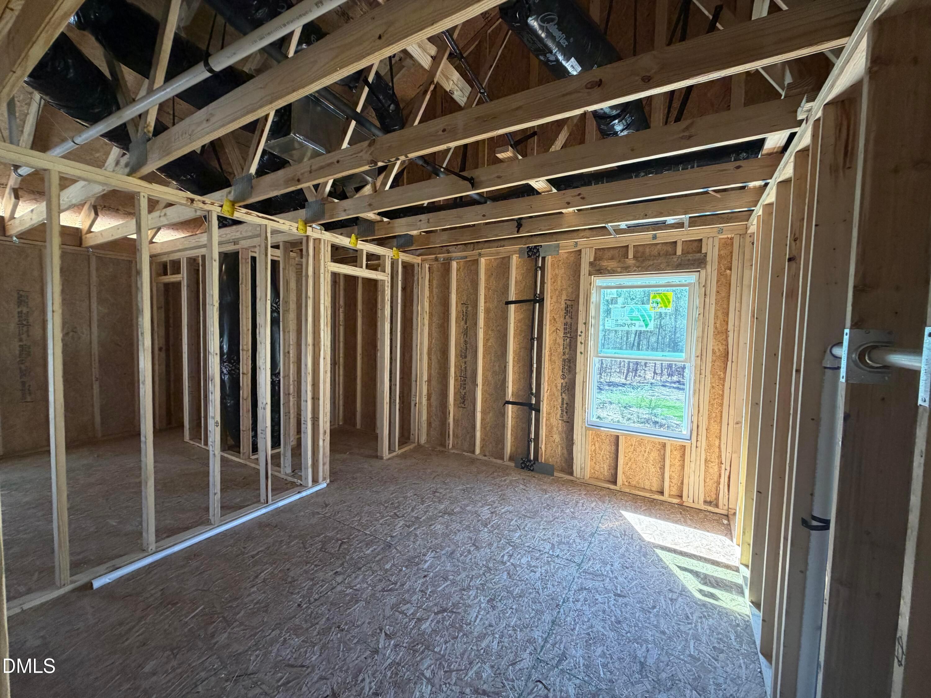 Exposed wooden framing and trusses in open room with window and ductwork during construction of Hickory II B 5-bedroom home, Lillington NC