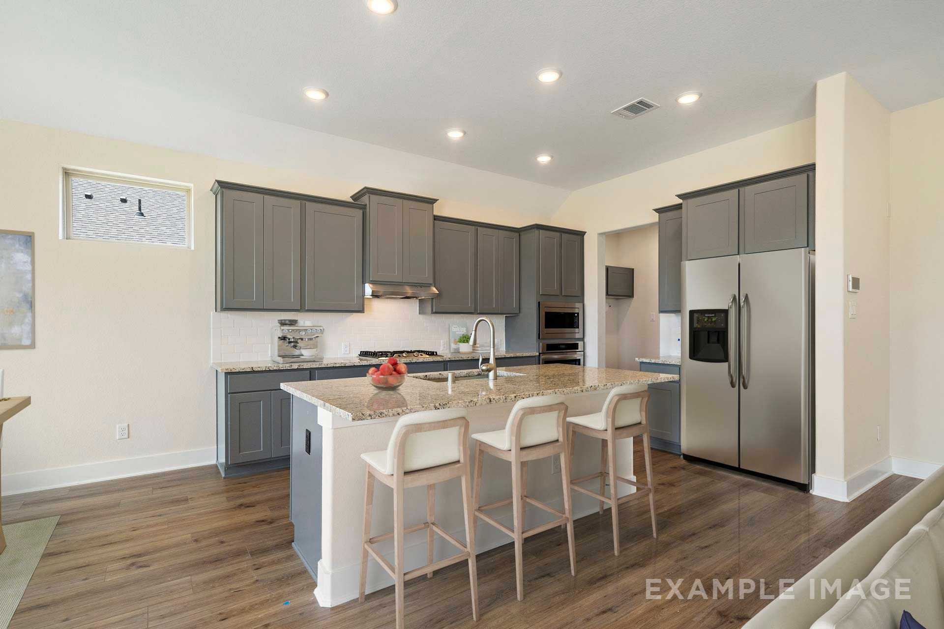 Spacious modern kitchen in The Diana C by Davidson Homes featuring gray shaker cabinets, white quartz island, stainless steel appliances, and hardwood floors