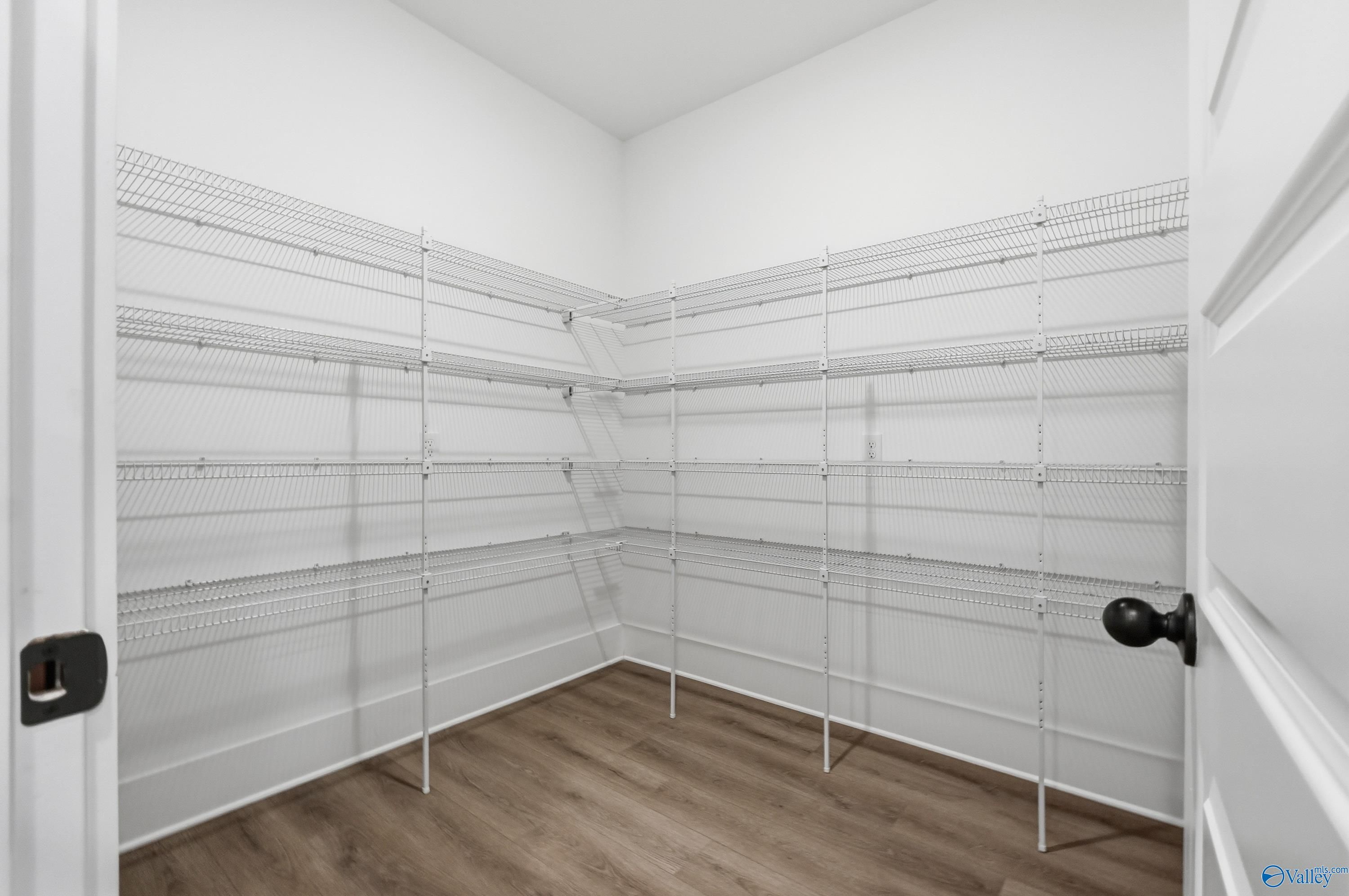 Spacious walk-in pantry with white wire shelving and laminate flooring in Davidson Homes The Finleigh, Meridianville, Alabama