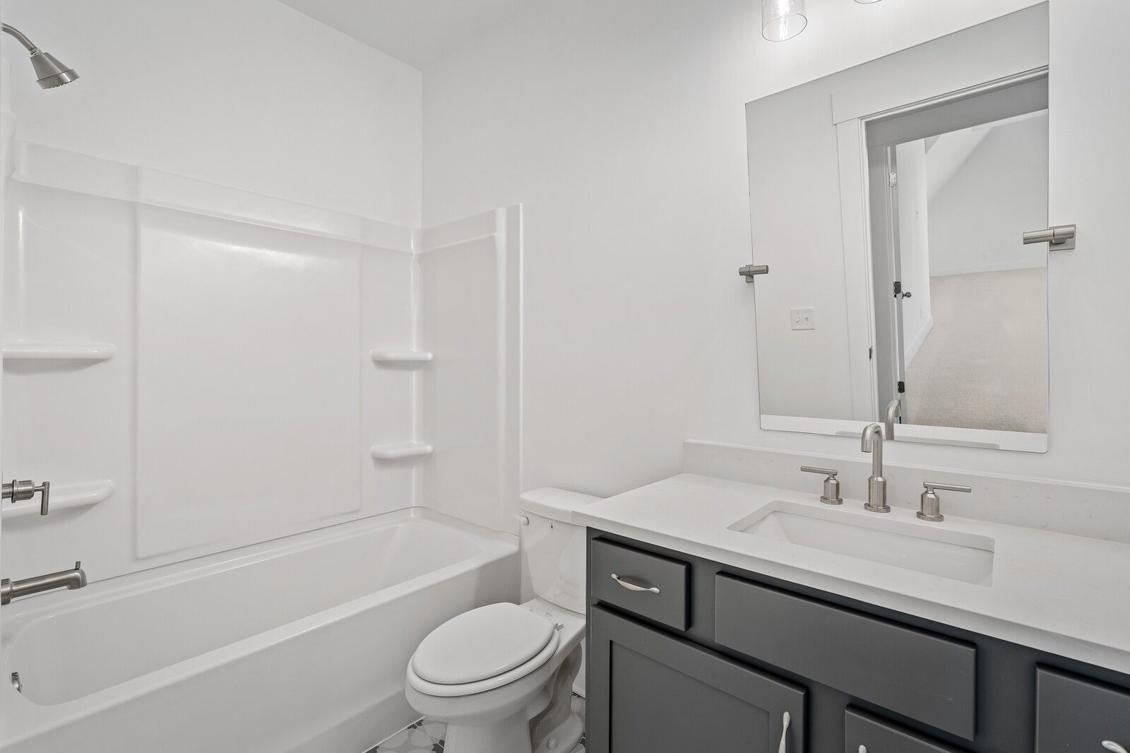 Bright bathroom with white tub-shower combo, gray vanity, single sink, and toilet in The Hawkins floor plan, Murfreesboro, Tennessee