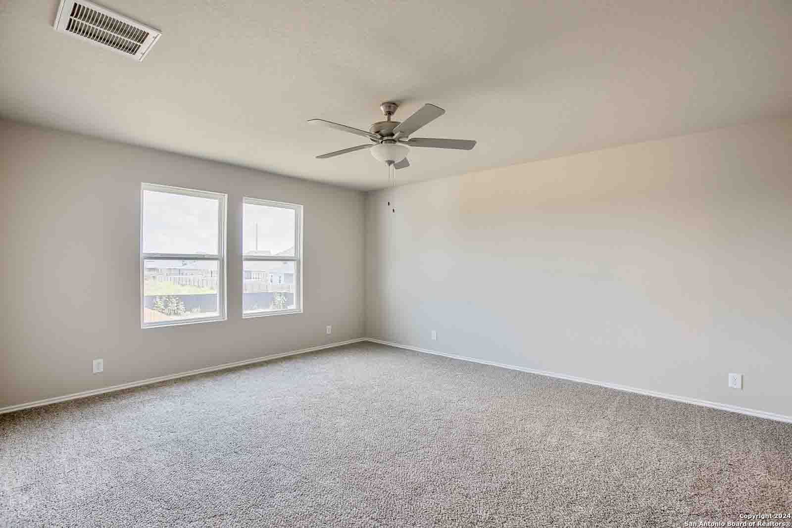 Bright secondary bedroom with large windows, ceiling fan, and beige carpet in Davidson Homes The Murray H, Seguin, Texas