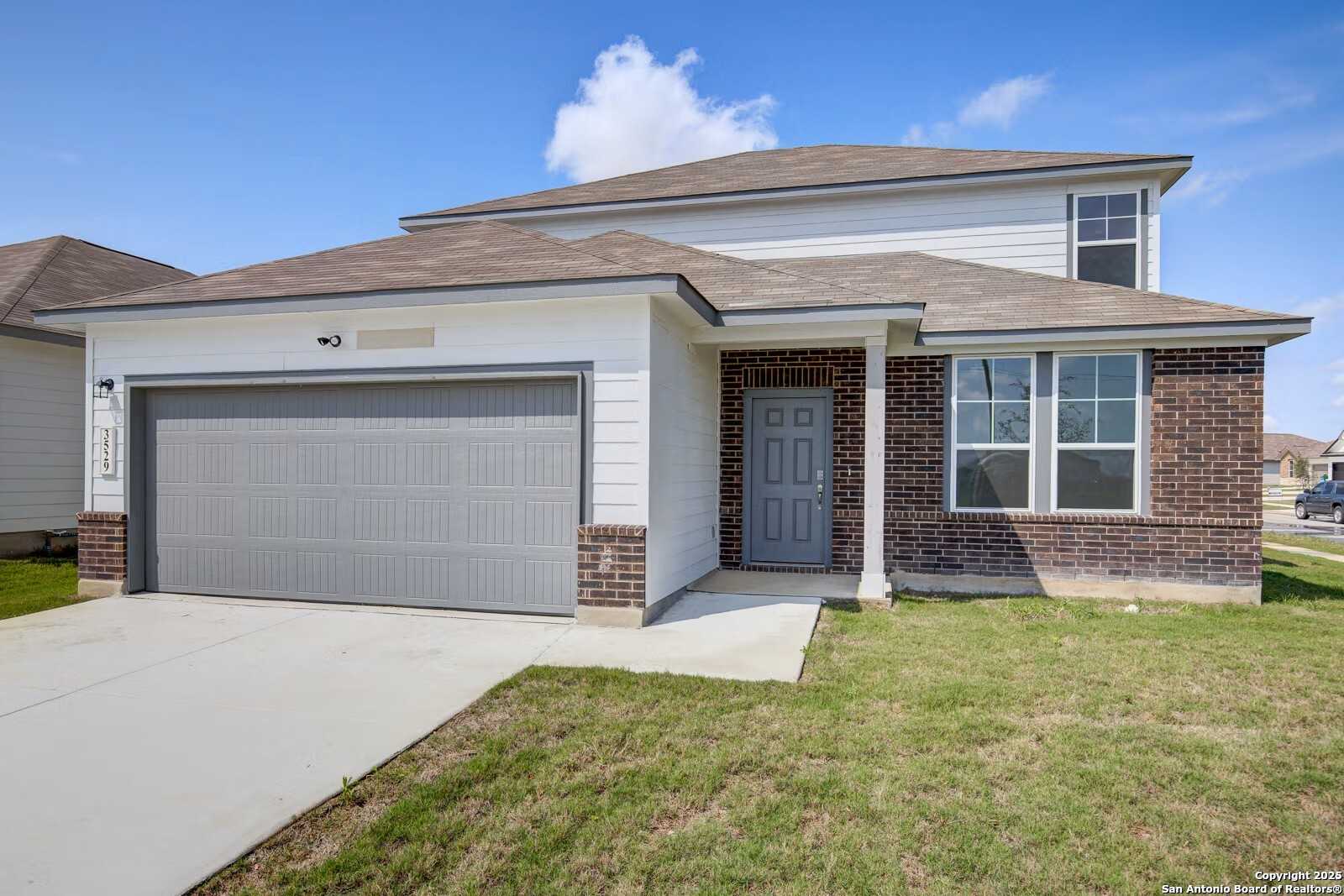 2-story beige brick home with gray 2-car garage and front door in Hannah Heights, Seguin, Texas - Davidson Homes Douglas B