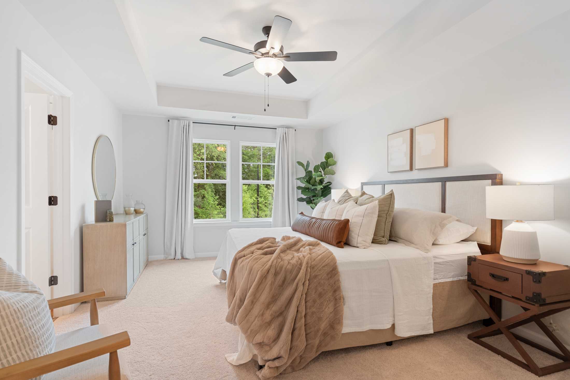 Spacious primary bedroom at Rosehill Townhomes in Marietta GA with king bed, neutral decor, ceiling fan and large windows