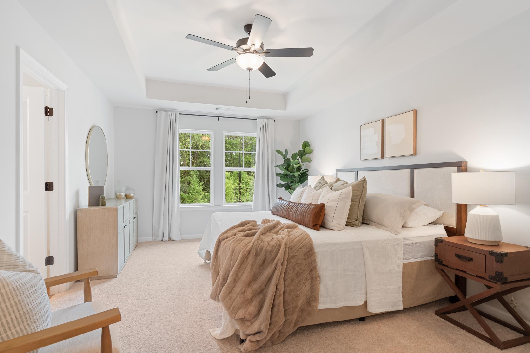 Spacious primary bedroom at Rosehill Townhomes in Marietta GA with king bed, neutral decor, ceiling fan and large windows