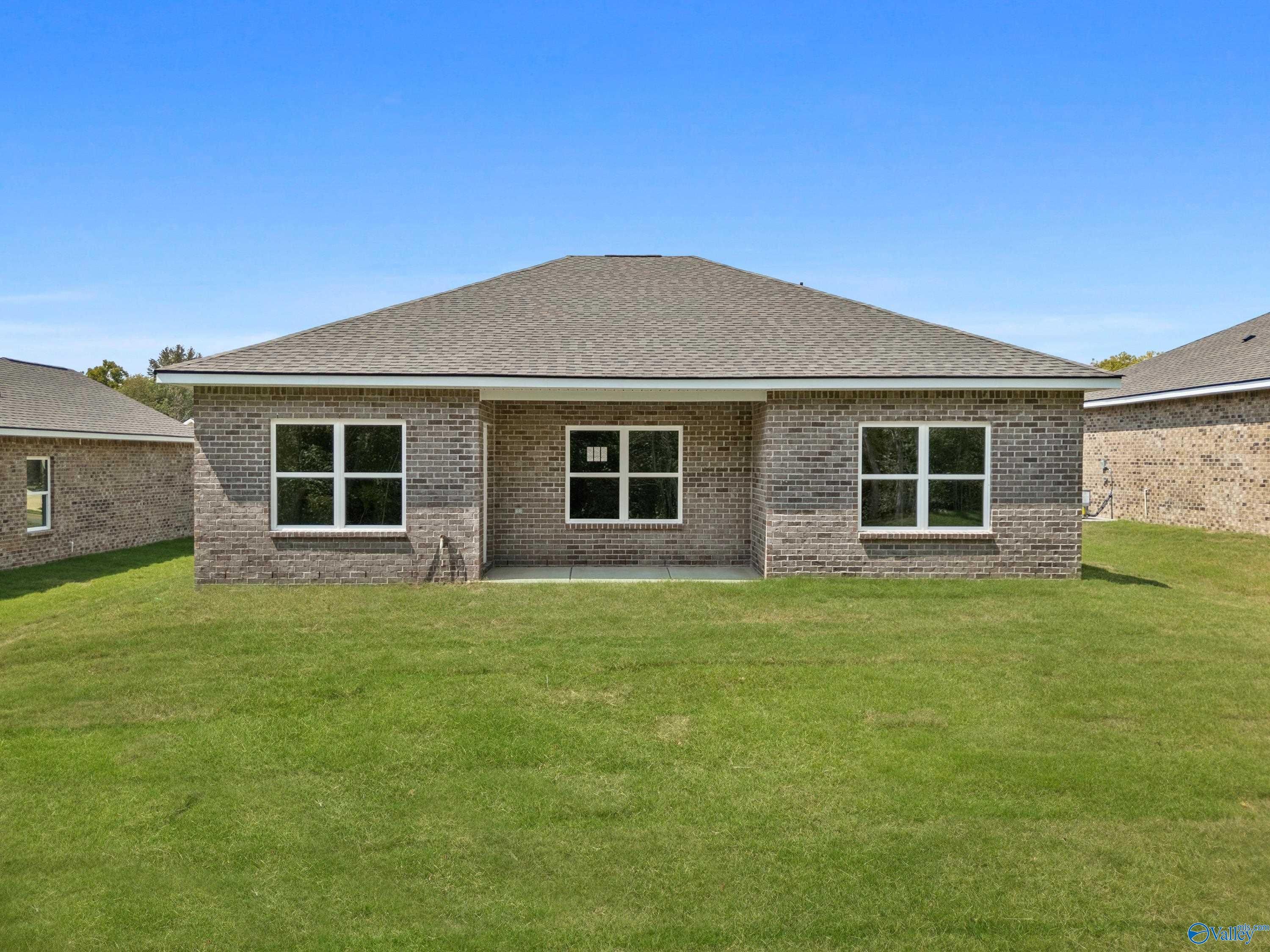 Rear view of single-story brick home with covered patio, large windows, and green lawn in Spragins Cove, Huntsville, Alabama by Davidson Homes The Asheville