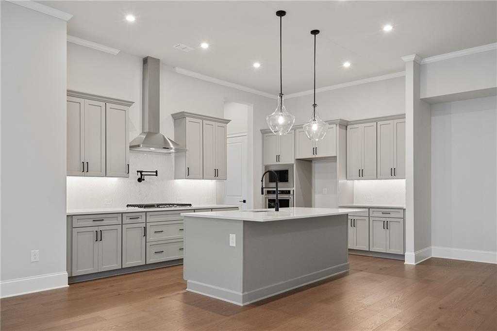 Modern gray shaker kitchen with oversized island, stainless appliances, and pendant lights in Davidson Homes Seaside B, Woodstock, GA