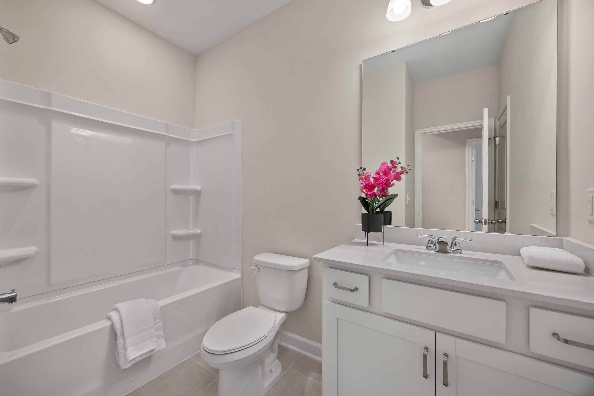 Modern bathroom with white vanity and tub-shower combo at Gregory Village in Lillington, NC by Davidson Homes.