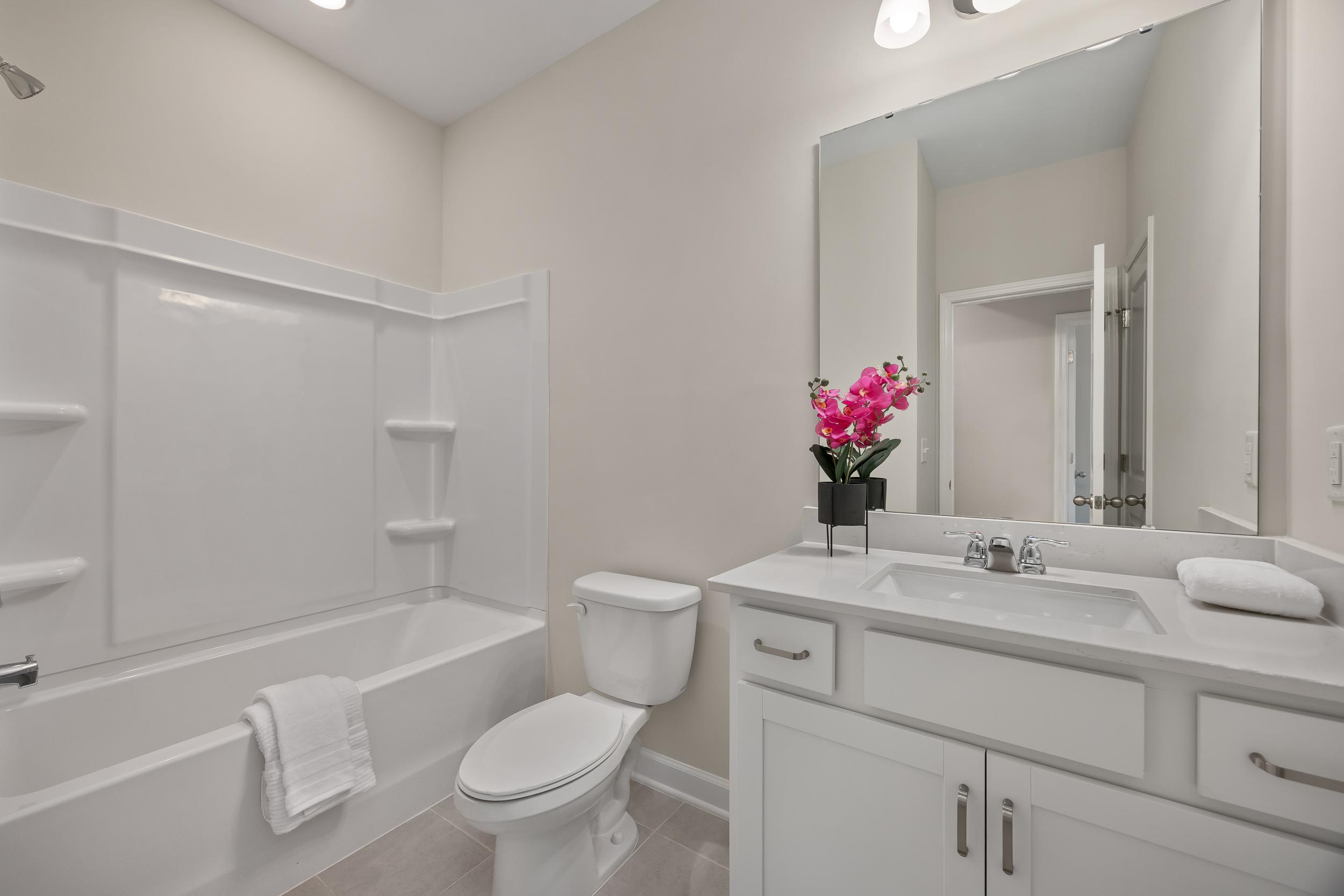 Modern bathroom with white vanity and tub-shower combo at Gregory Village in Lillington, NC by Davidson Homes.