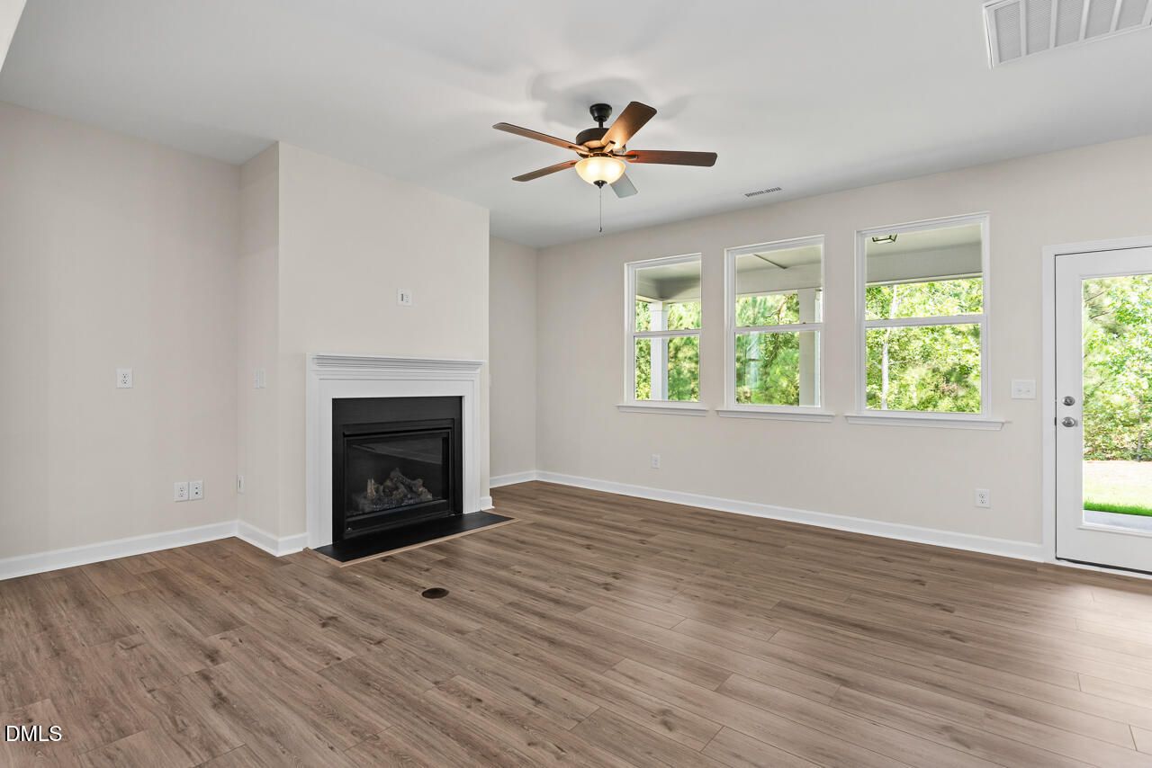 Bright great room with gas fireplace, ceiling fan, and hardwood floors in Davidson Homes The Birch II C, Wake Forest, NC
