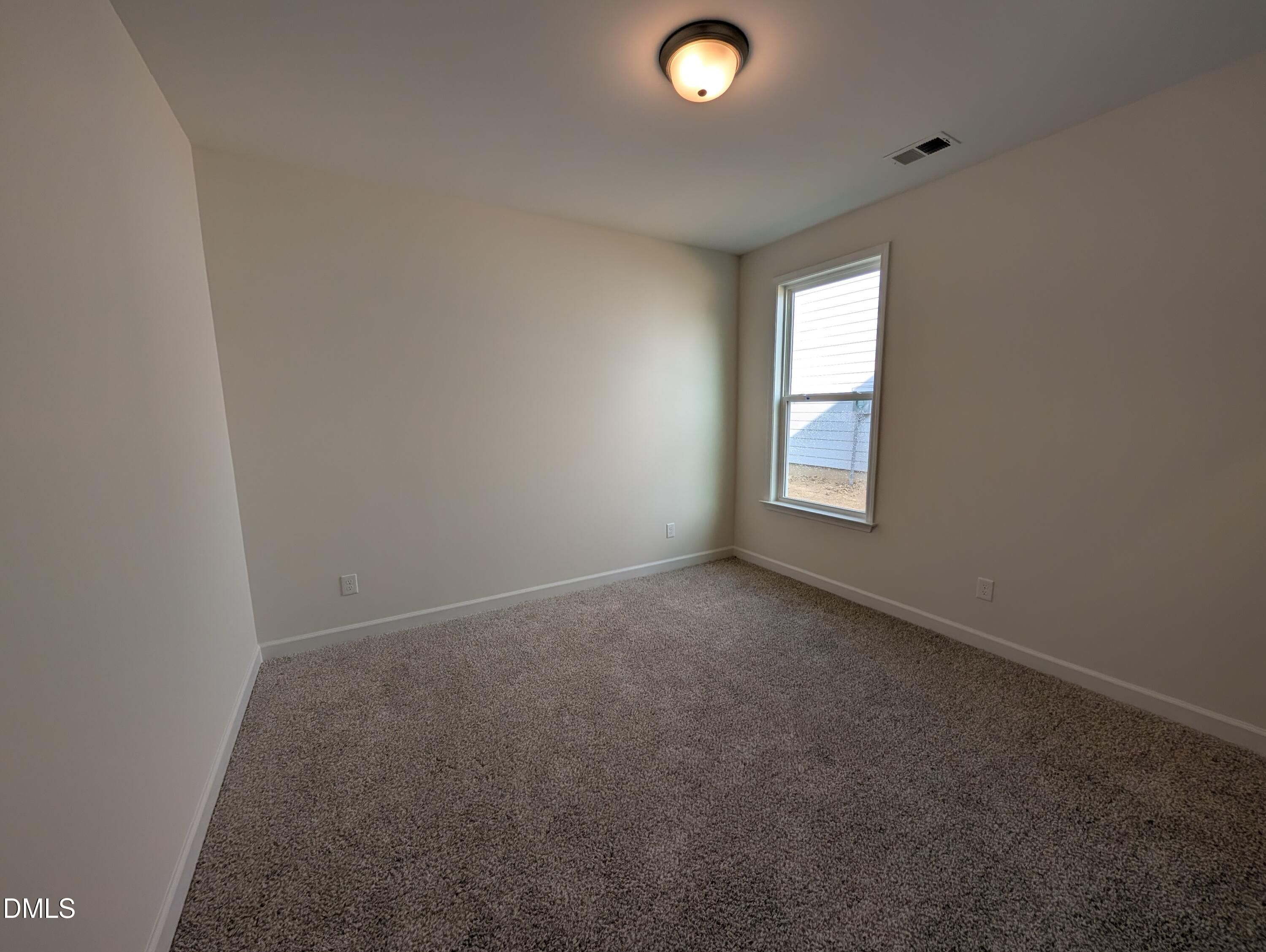 Empty bedroom with neutral walls, plush carpet, and window in Davidson Homes Magnolia A at Wendell Ridge, Wendell NC