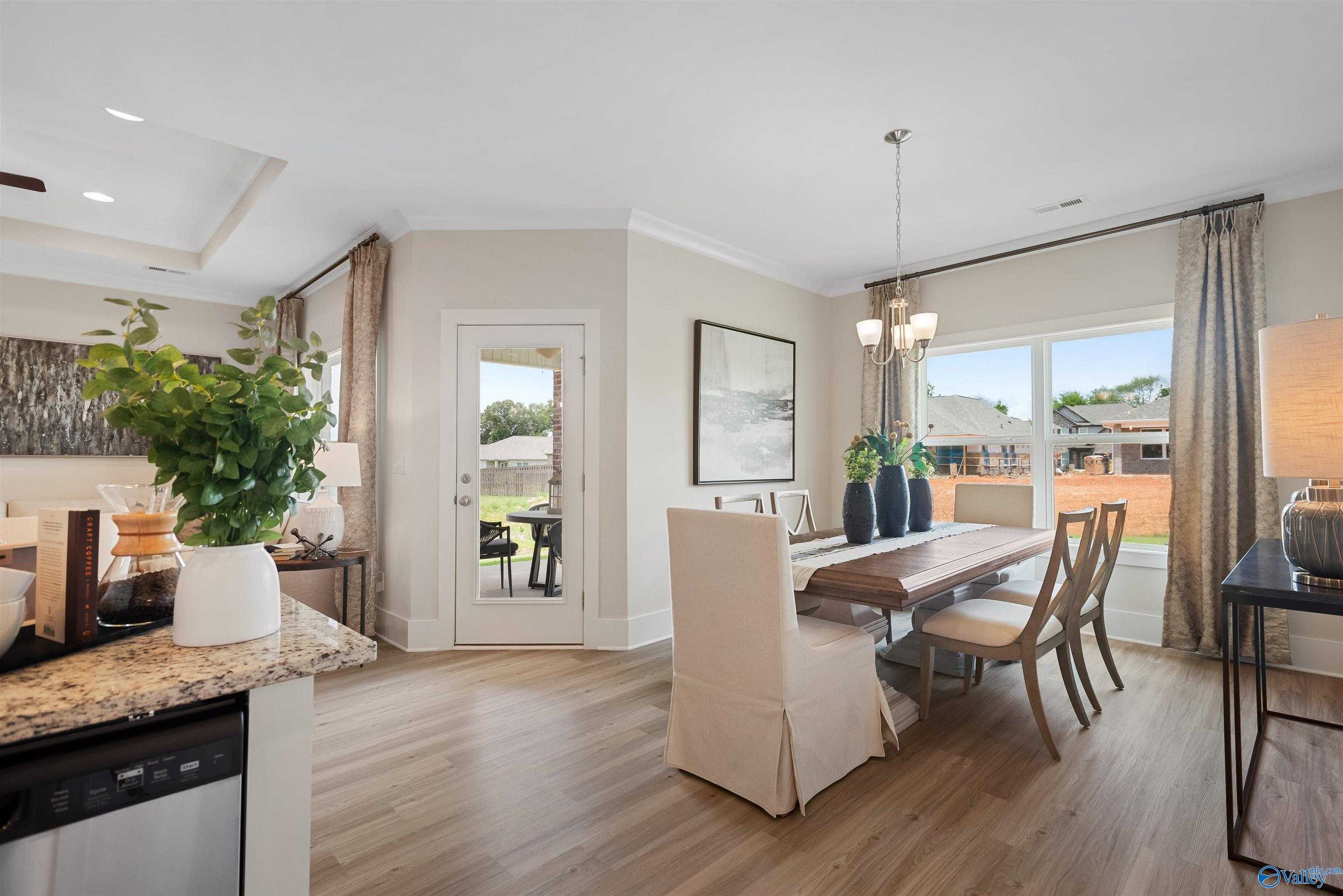 Elegant dining room with wooden table, upholstered chairs, and granite kitchen island in Davidson Homes The Everett, New Market, Alabama