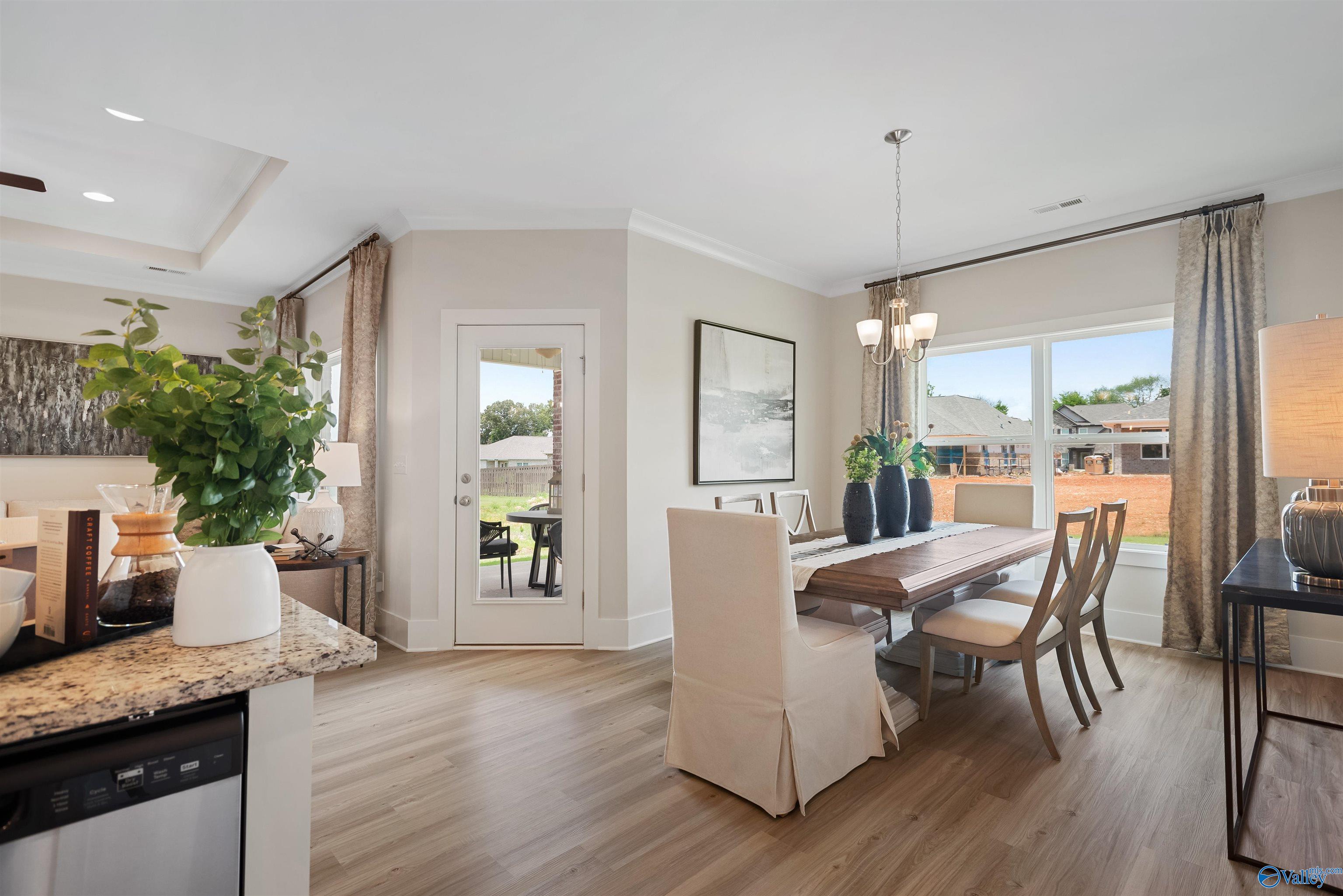 Elegant dining room with wooden table, upholstered chairs, and granite kitchen island in Davidson Homes The Everett, New Market, Alabama