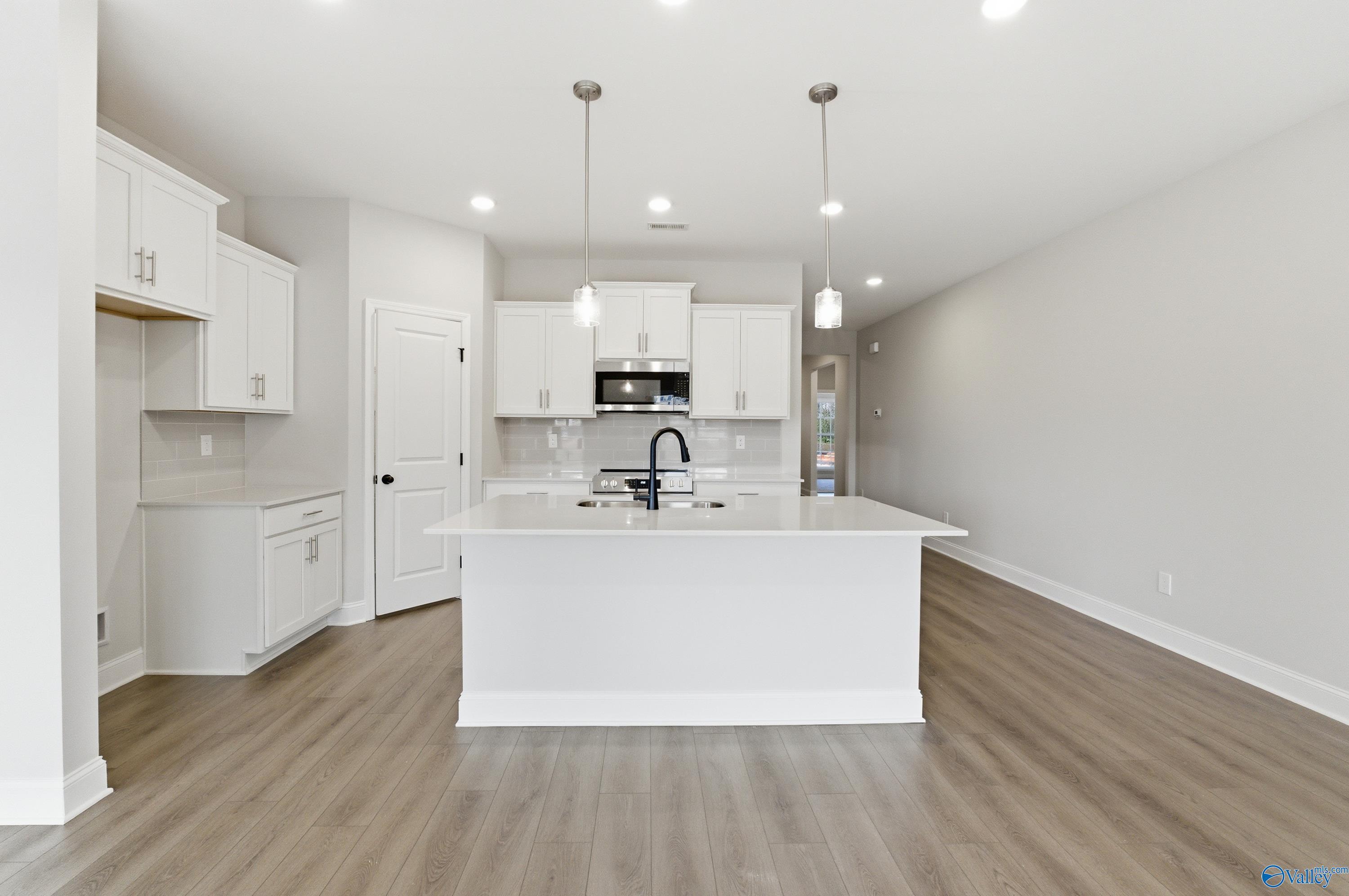 Modern white kitchen island with stainless sink and cabinetry in Davidson Homes The Daphne C, Huntsville Alabama