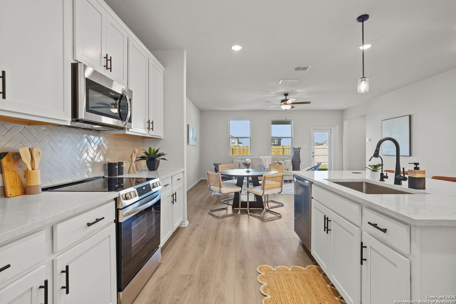 Modern open-concept kitchen with white cabinets, stainless appliances, subway tile backsplash, and dining nook in Davidson Homes The Douglas C, Seguin, Texas