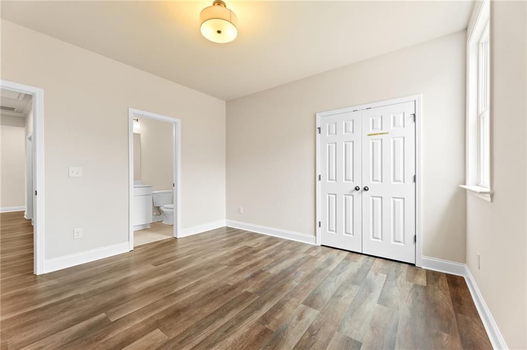 Spacious bedroom featuring hardwood floors, double-door closet, and adjacent bath in Davidson Homes Harrison H, Winder, GA
