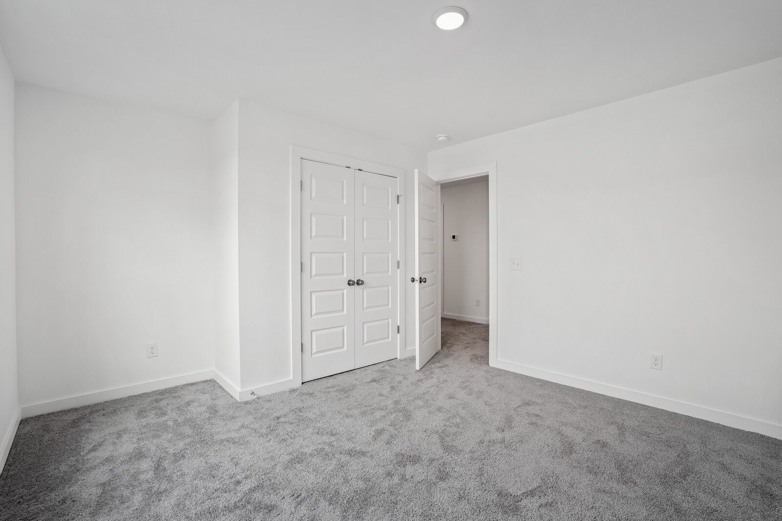 Bright bedroom with neutral carpet and double closet doors in The Logan B floor plan at Calista Farms, White House, TN.