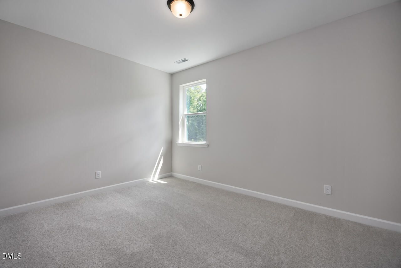 Bright, neutral-toned bedroom with plush carpet in The Ashport L floor plan at Sage on North Main, Wake Forest, NC.
