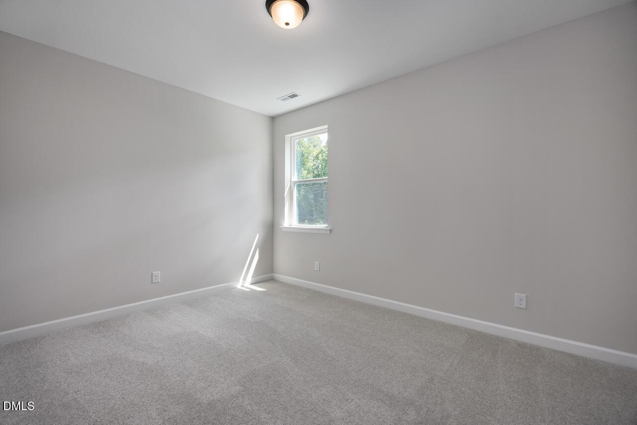 Bright, neutral-toned bedroom with plush carpet in The Ashport L floor plan at Sage on North Main, Wake Forest, NC.
