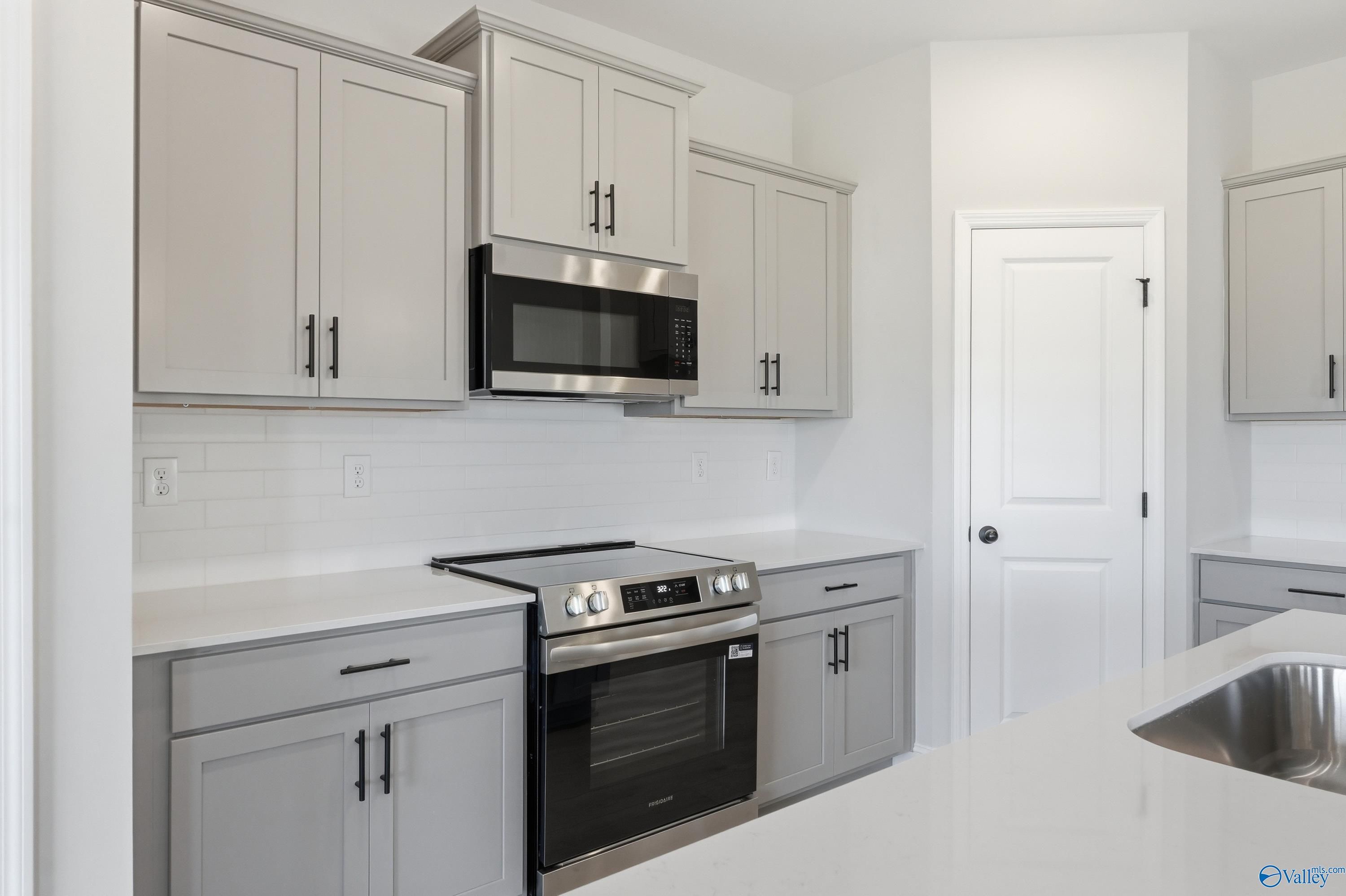 Modern kitchen with gray shaker cabinets, stainless steel appliances, subway tile backsplash in Davidson Homes The Franklin C, New Market, AL