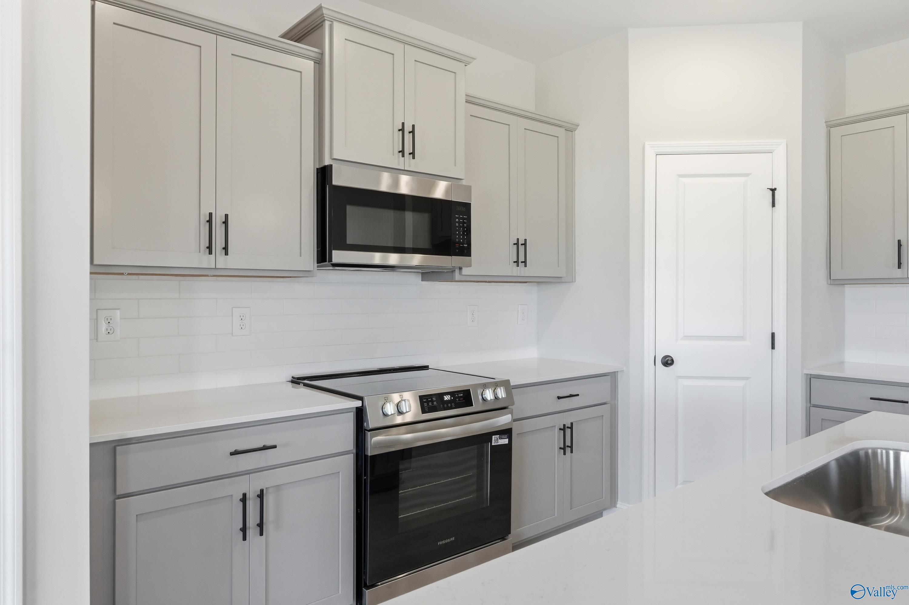 Modern kitchen with gray shaker cabinets, stainless steel appliances, subway tile backsplash in Davidson Homes The Franklin C, New Market, AL
