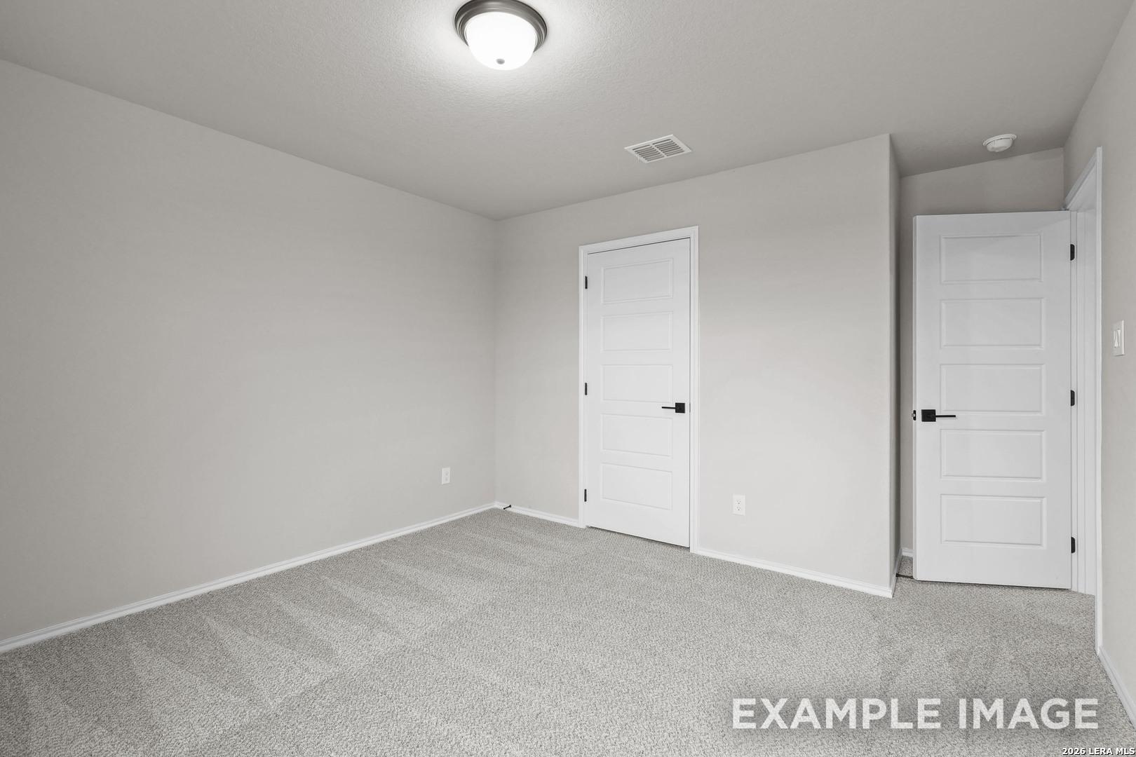Empty bedroom with gray carpet, neutral walls, and white doors in Davidson Homes The Murray H plan, Converse, TX
