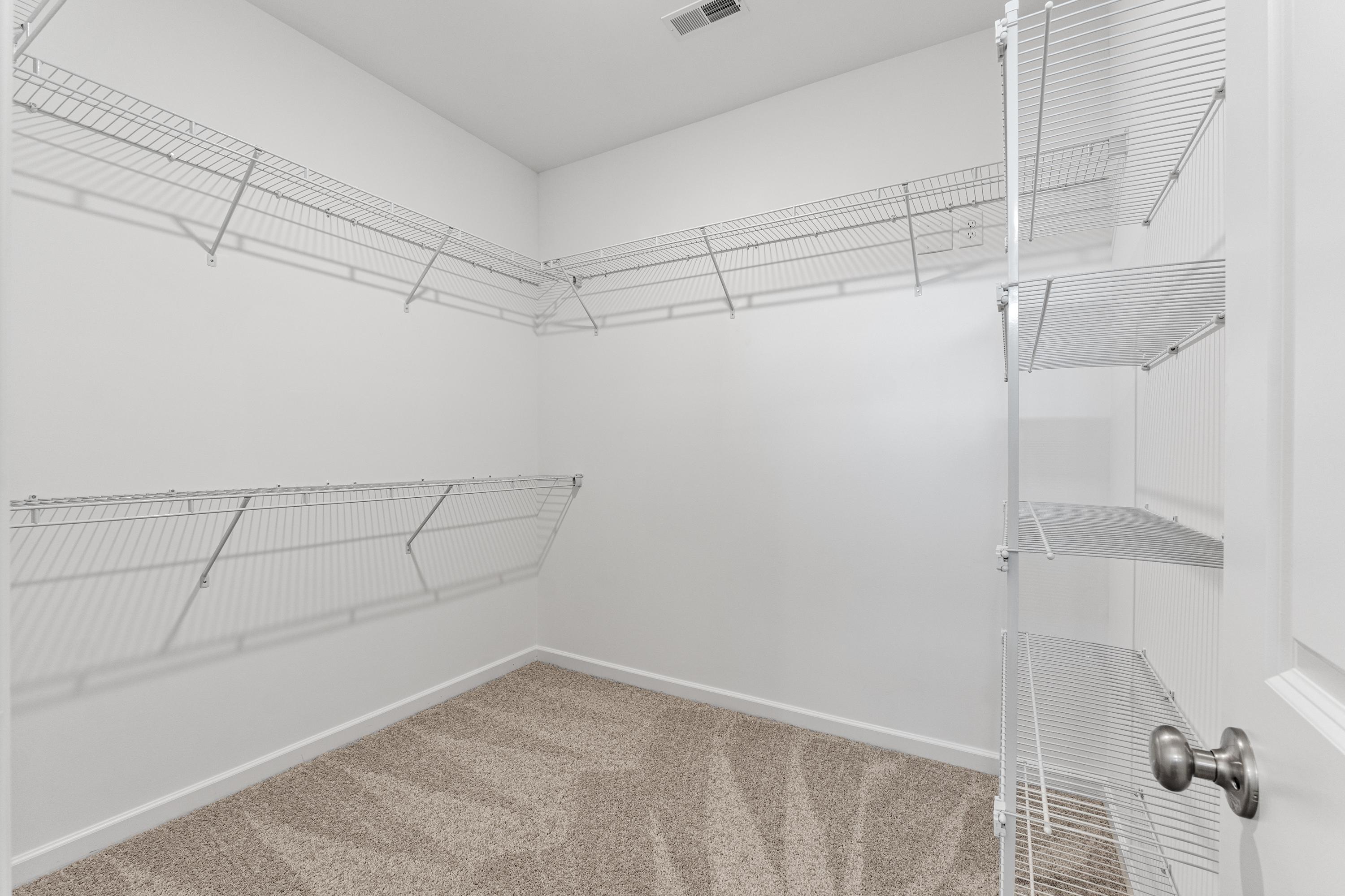 Spacious master walk-in closet in The Haven with white wire shelving, beige carpet floor