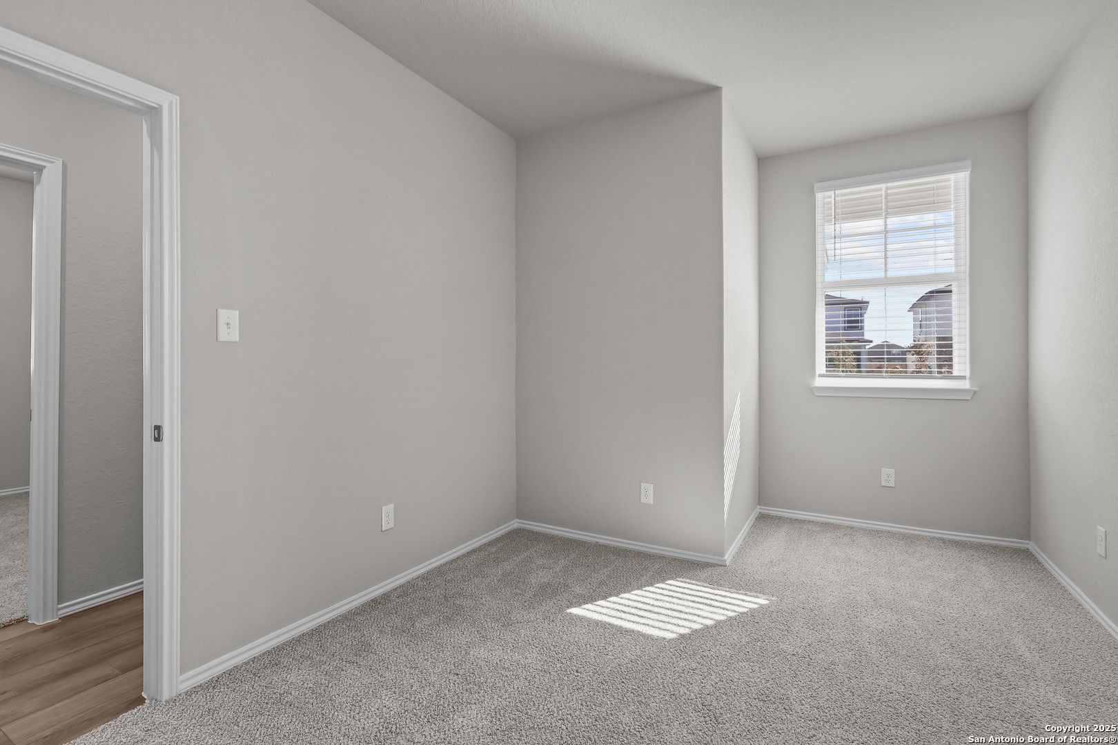 Sunlit secondary bedroom with gray walls, carpet flooring, and blinds-covered window in Davidson Homes The Colorado B, San Antonio