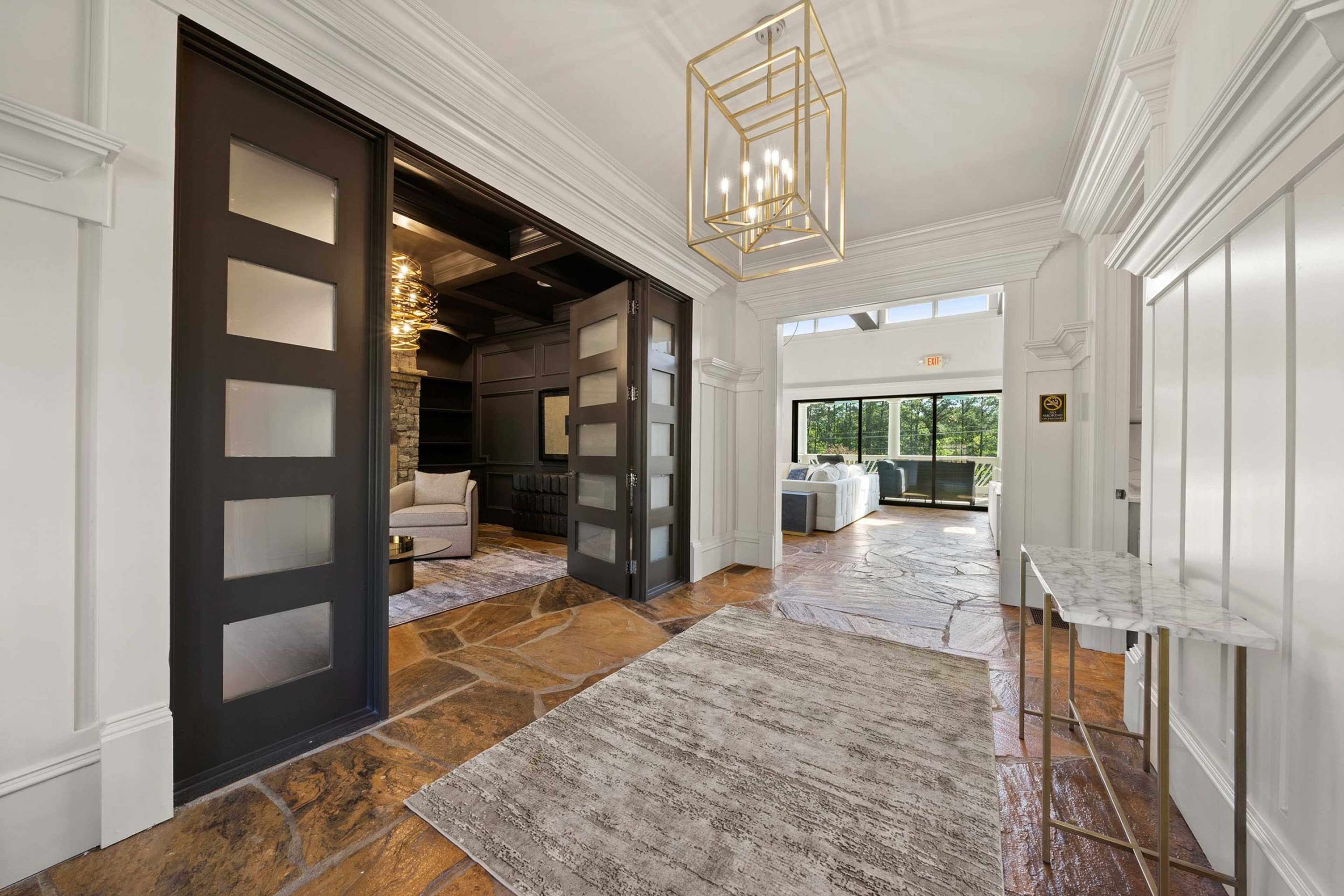 Elegant foyer with gold chandelier, glass doors, stone floors, and lounge seating at Mountainbrook in Cartersville, Georgia