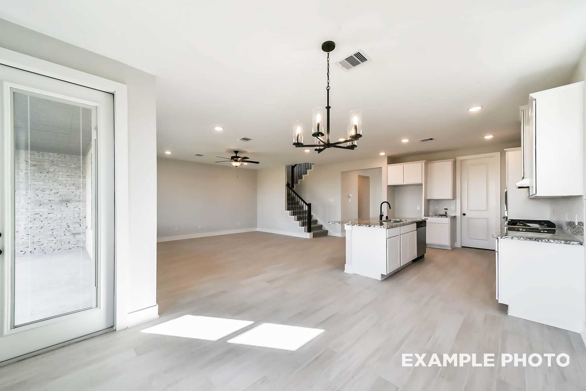 Modern open kitchen with white island, chandelier, and French doors in Davidson Homes The Philip C, Rosharon, Texas