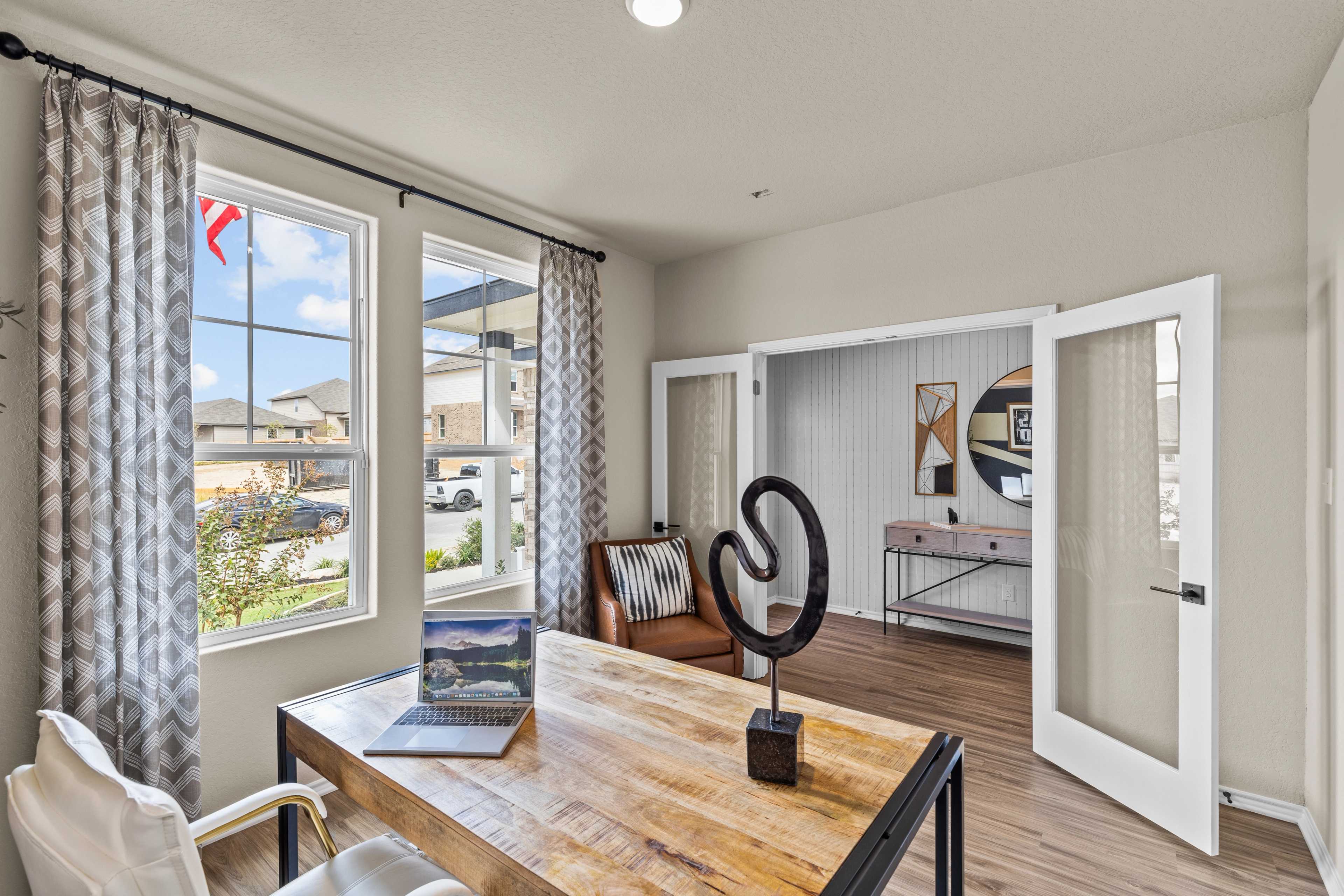 Spacious home office in Morgan Meadows San Antonio TX with wooden desk laptop leather chair large windows and modern decor