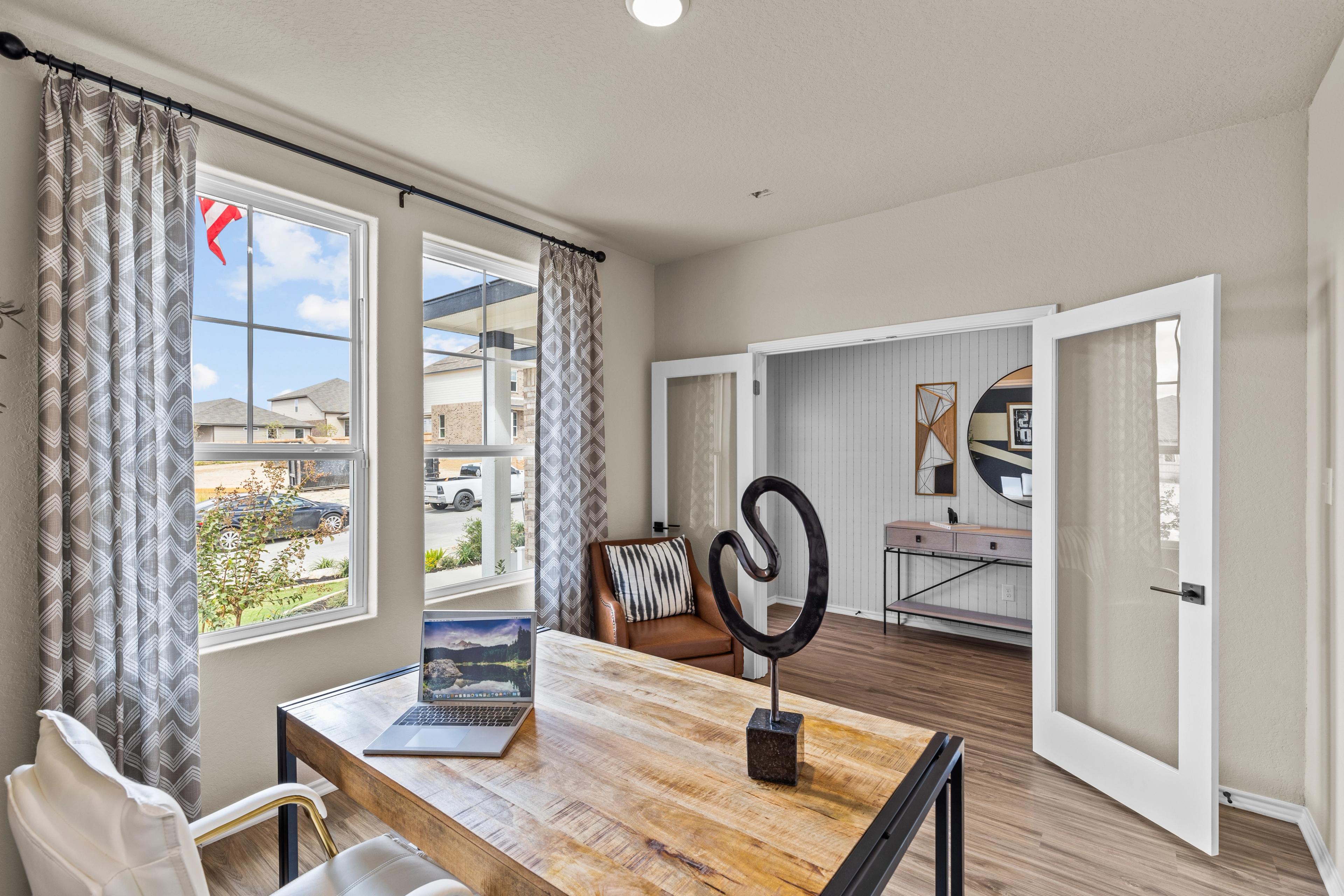 Spacious home office in Morgan Meadows San Antonio TX with wooden desk laptop leather chair large windows and modern decor