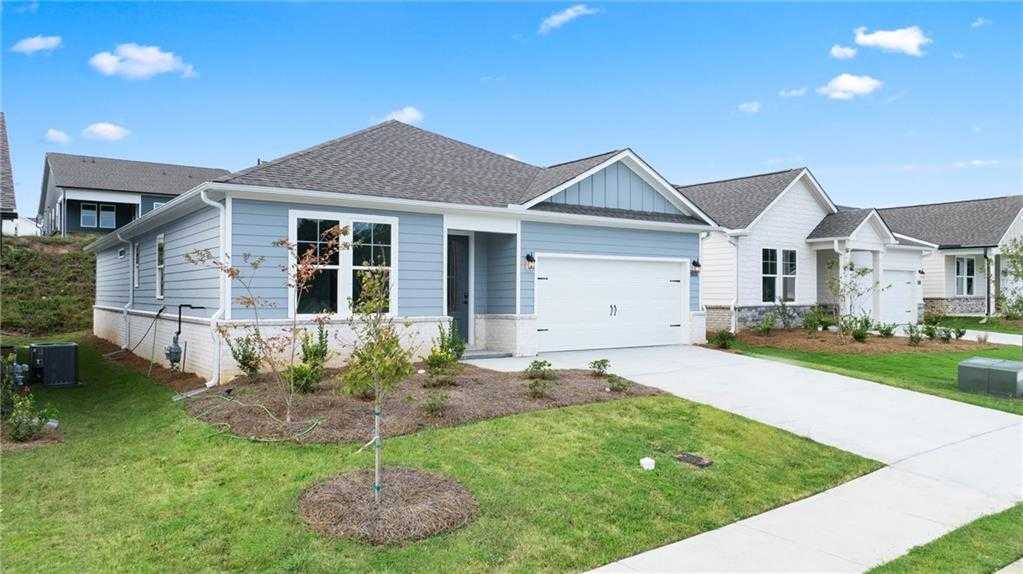 Light blue single-story Daphne C home with 2-car garage, concrete driveway, and lush front yard landscaping in Kelly Preserve, Loganville, GA