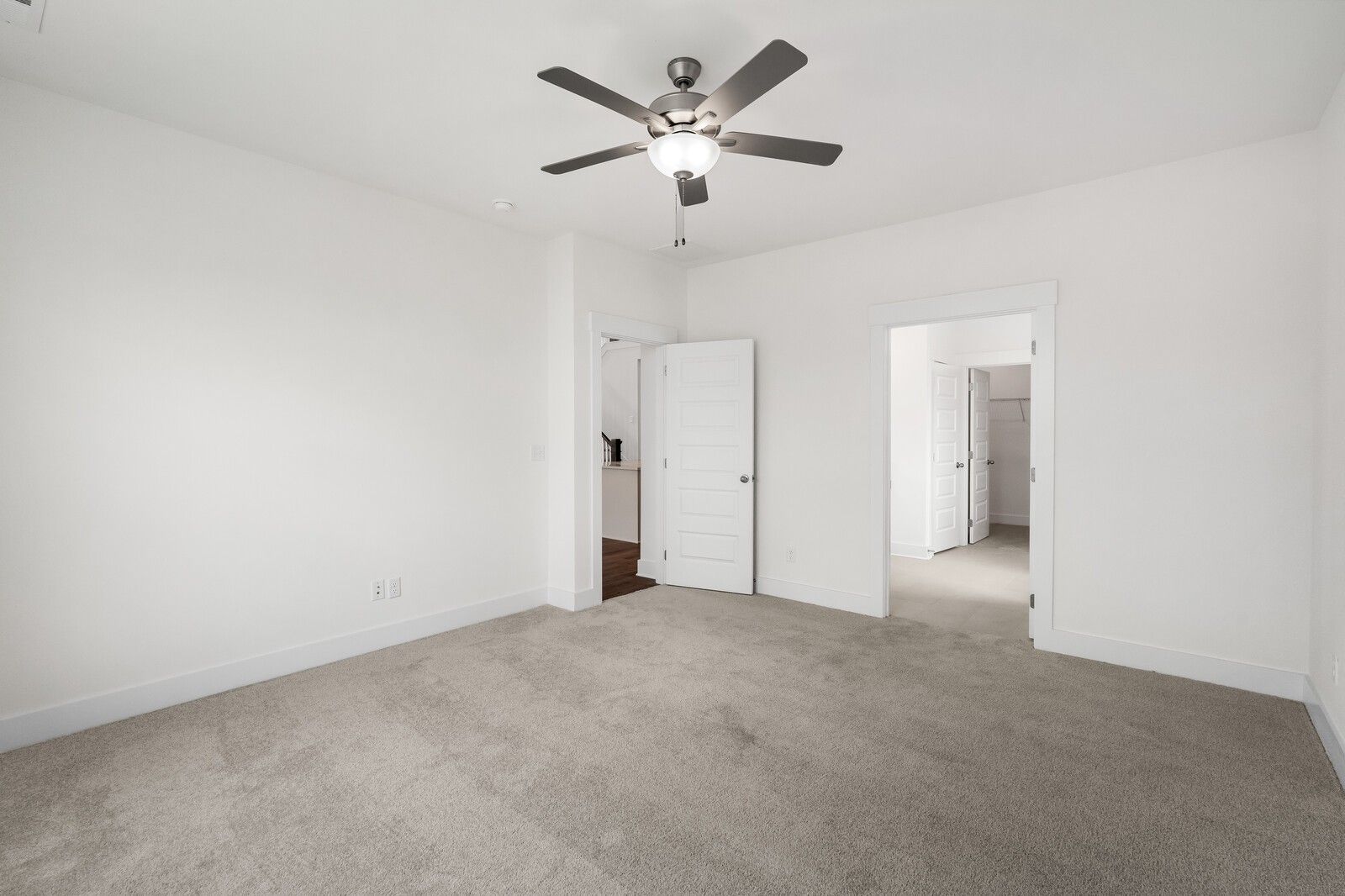 Spacious bedroom with ceiling fan, white walls, carpet floor, and adjacent doors in Davidson Homes The Ridgeport, Gallatin, TN