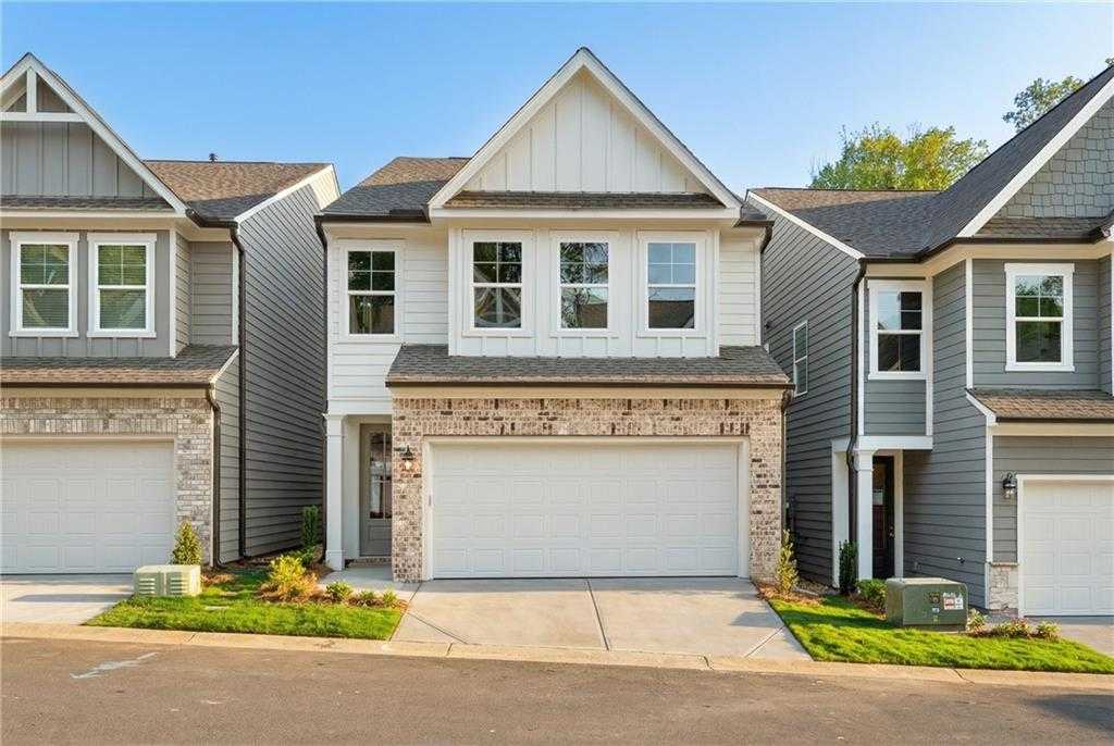 Modern two-story home with white siding, brick accents, 2-car garage, and lush landscaping in The Village at Shallowford, Kennesaw, Georgia