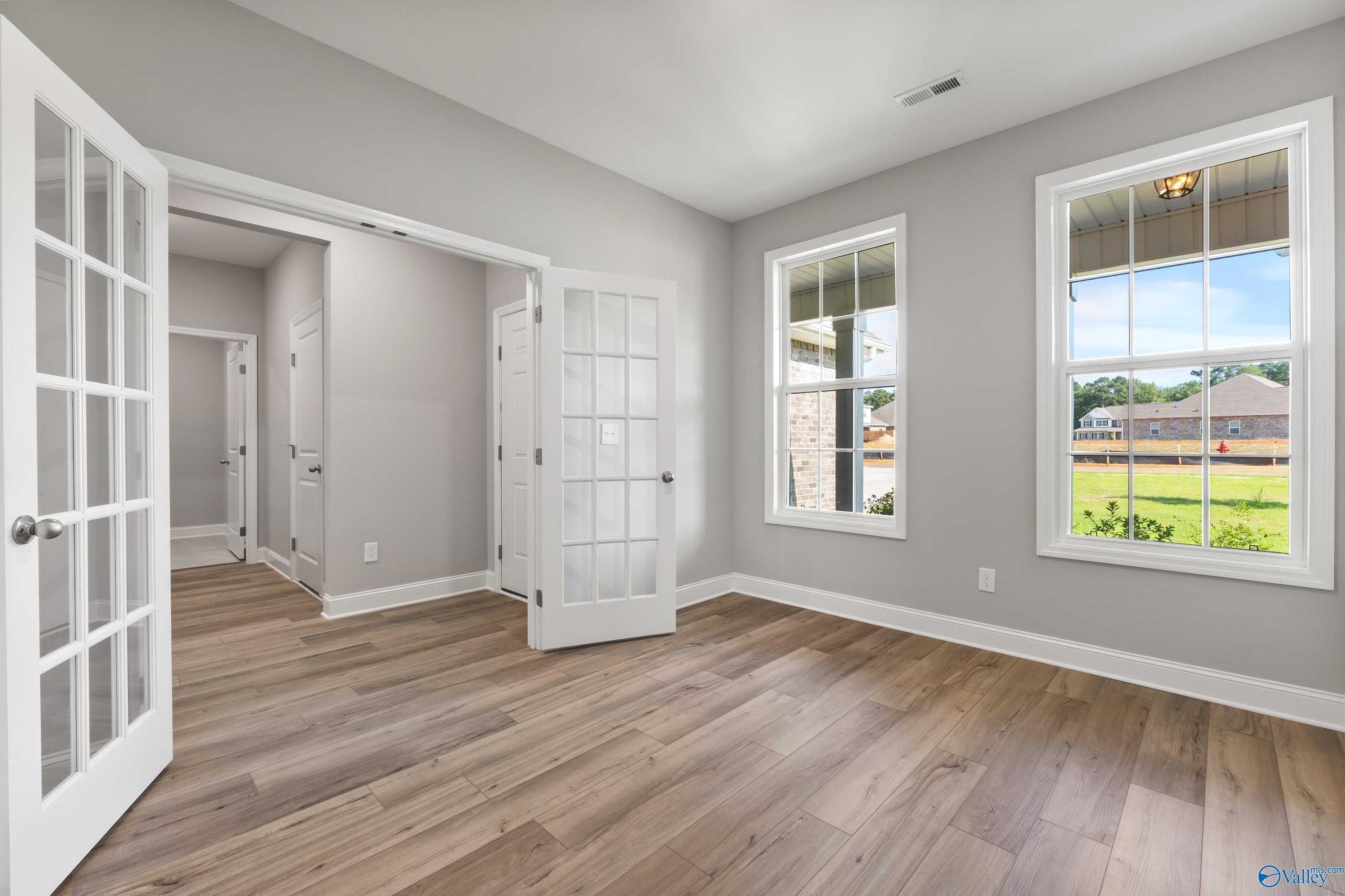 Bright flex room with open French doors, hardwood floors, and large windows overlooking lush backyard in Davidson Homes The Rockford, Harvest AL