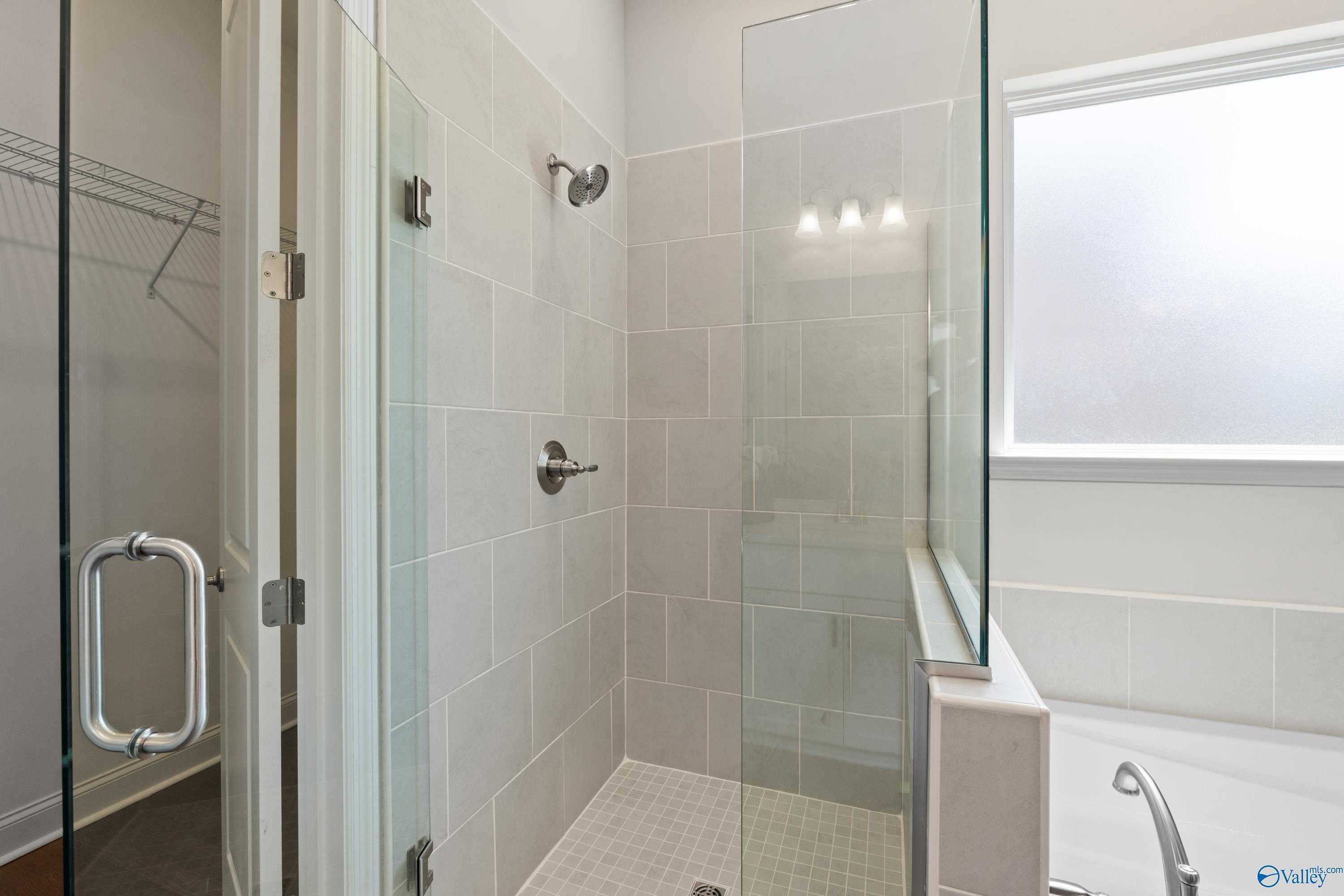 Modern master bathroom with frameless glass shower, subway tile walls, freestanding tub, walk-in closet in Evermore Homes The Haven, Owens Cross Roads