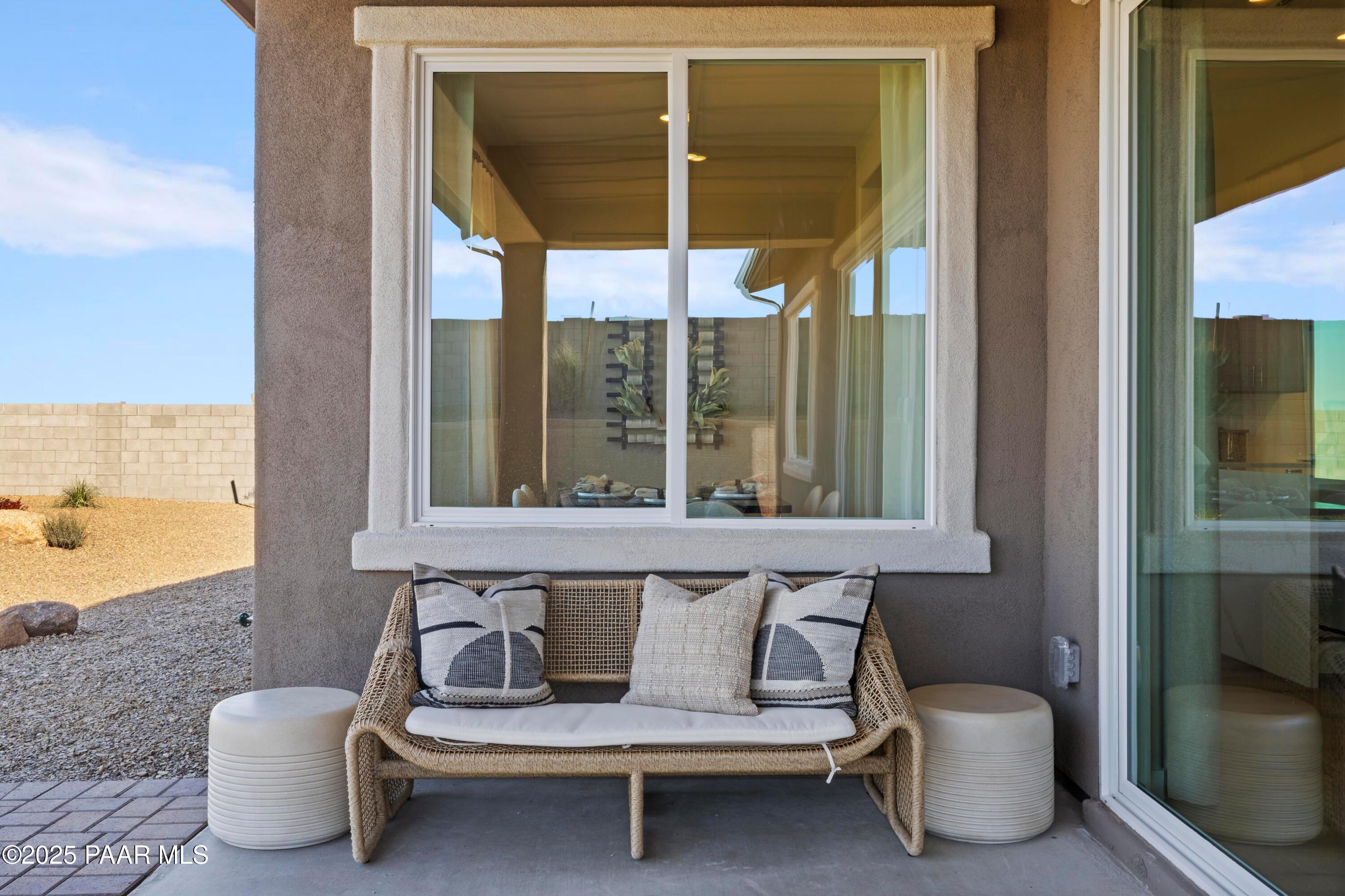 Cozy rattan sofa with patterned cushions on covered patio overlooking desert landscape in Davidson Homes The Blaze D, Prescott, Arizona