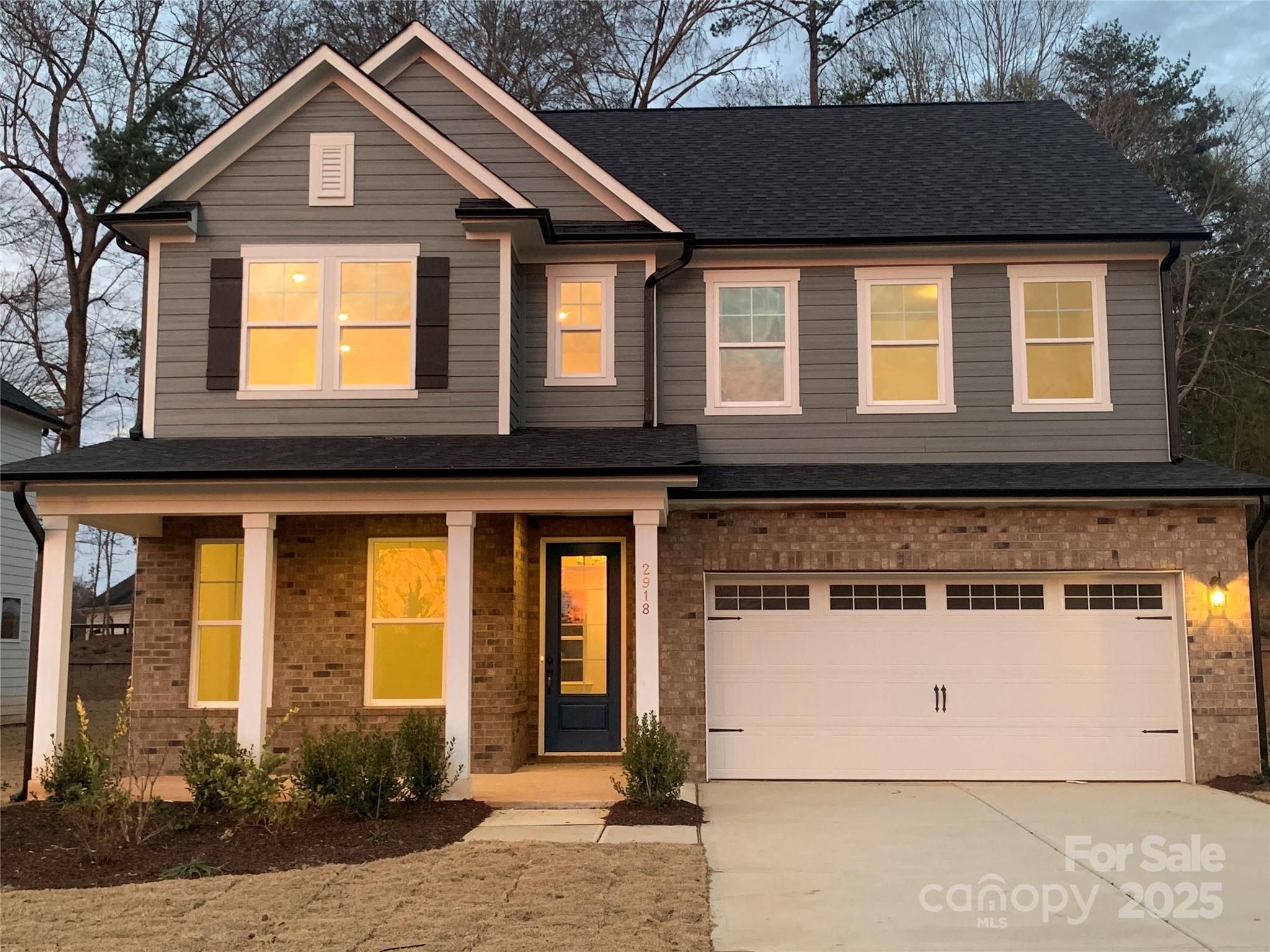 Two-story Chestnut F home by Davidson Homes in Enclave at Belmont: gray siding, brick accents, covered porch, two-car garage, Belmont, NC