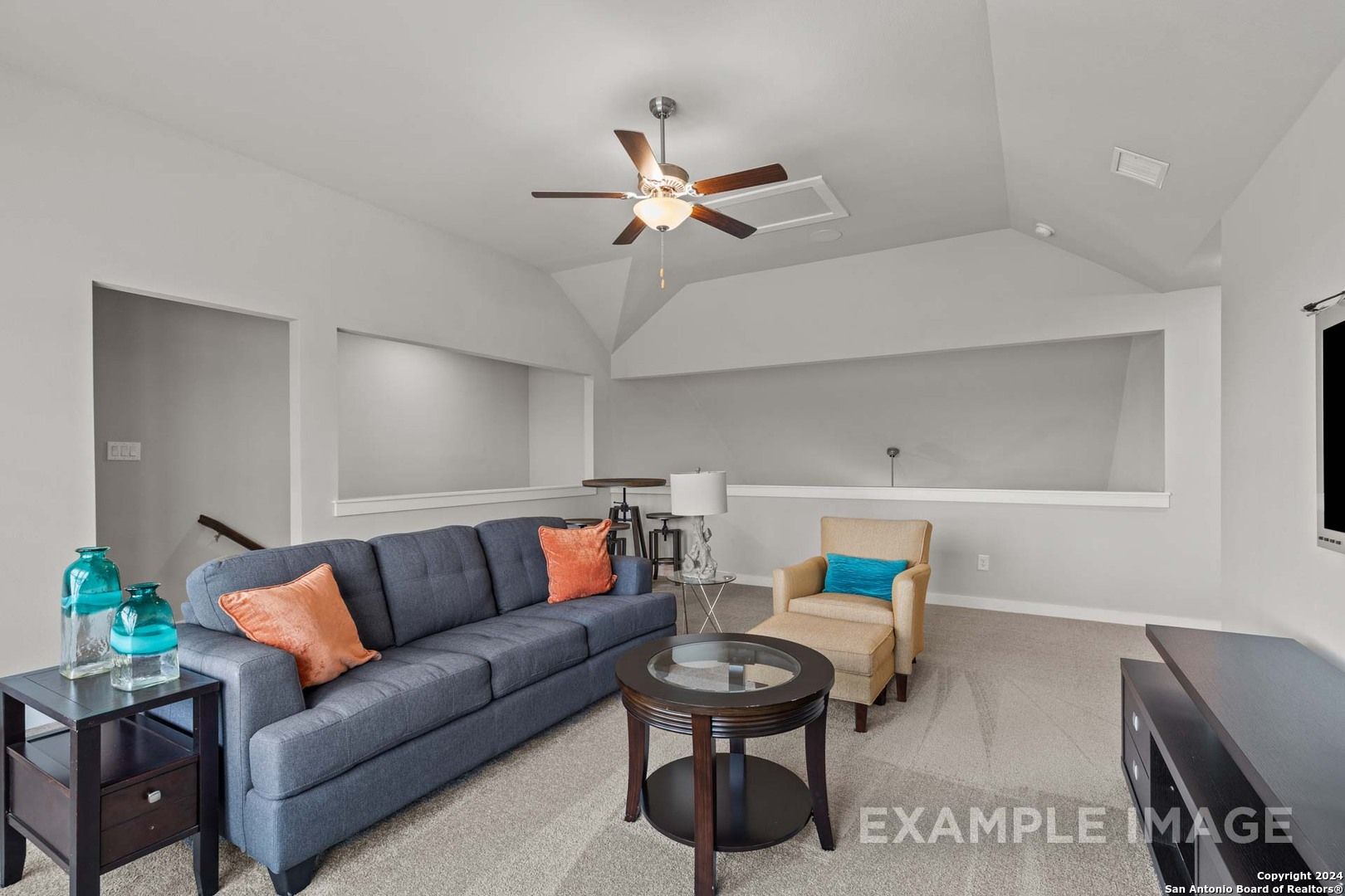 Cozy living room with navy sectional sofa, orange pillows, glass coffee table, and ceiling fan in Davidson Homes The Collin A, Seguin, Texas