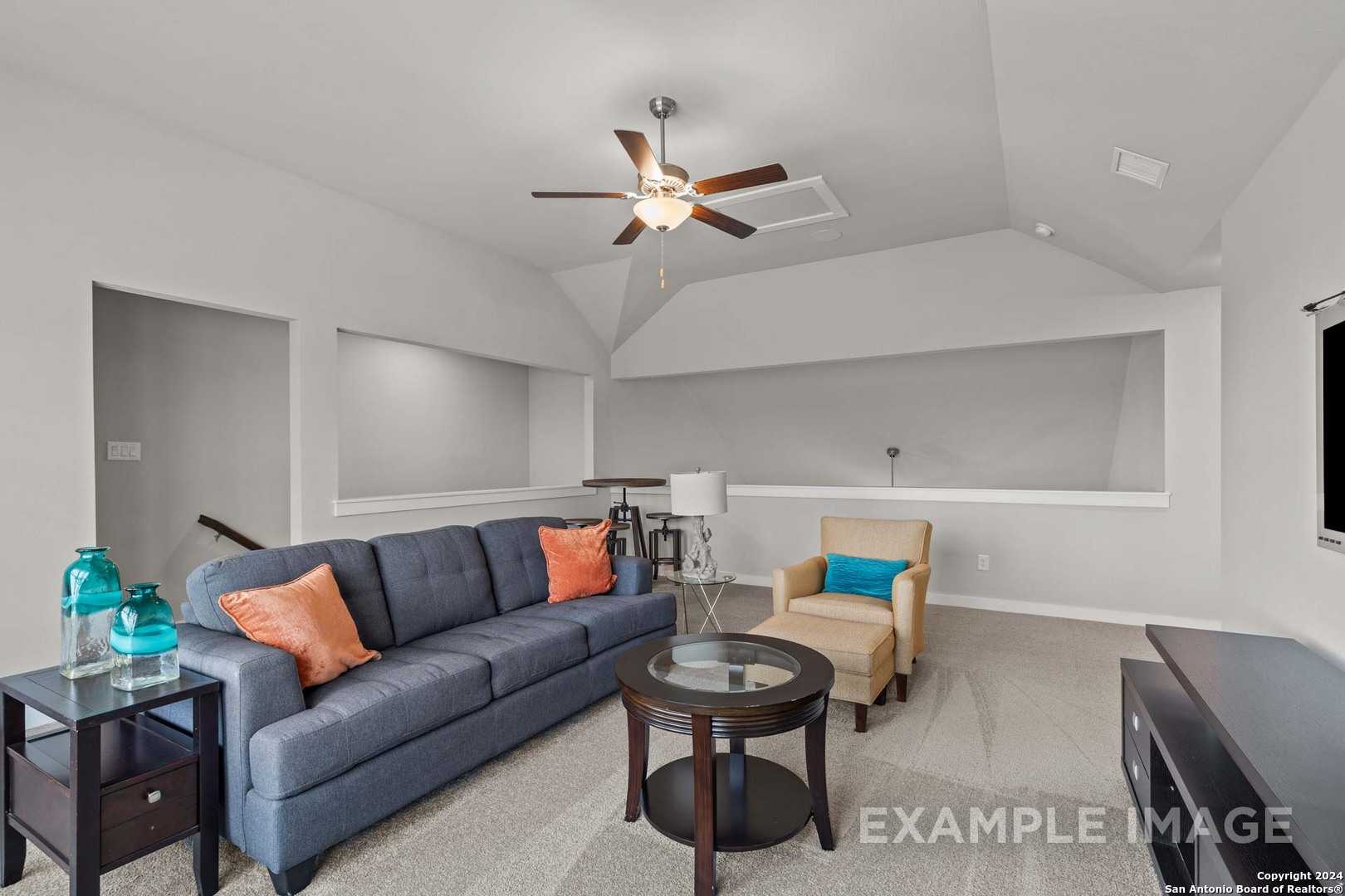 Cozy living room with navy sectional sofa, orange pillows, glass coffee table, and ceiling fan in Davidson Homes The Collin A, Seguin, Texas