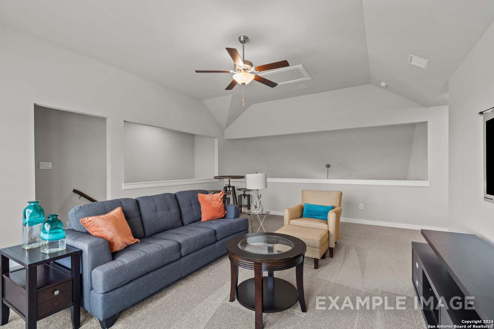 Cozy living room with navy sectional sofa, orange pillows, glass coffee table, and ceiling fan in Davidson Homes The Collin A, Seguin, Texas