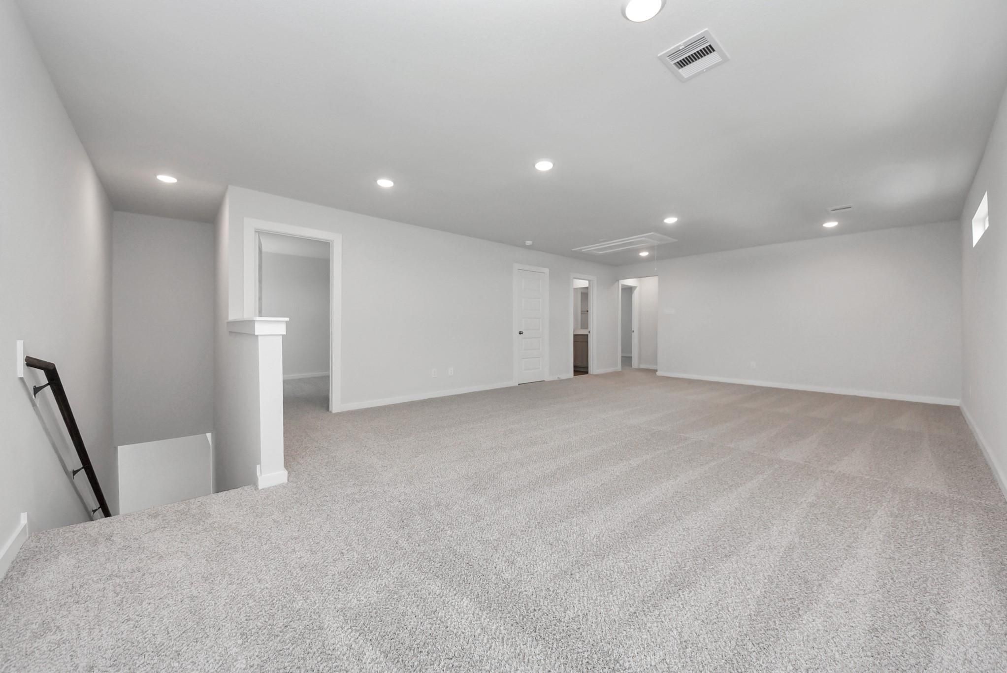 Spacious carpeted upstairs game room with recessed lighting in Davidson Homes The San Marcos E, Emberly, Beasley, Texas
