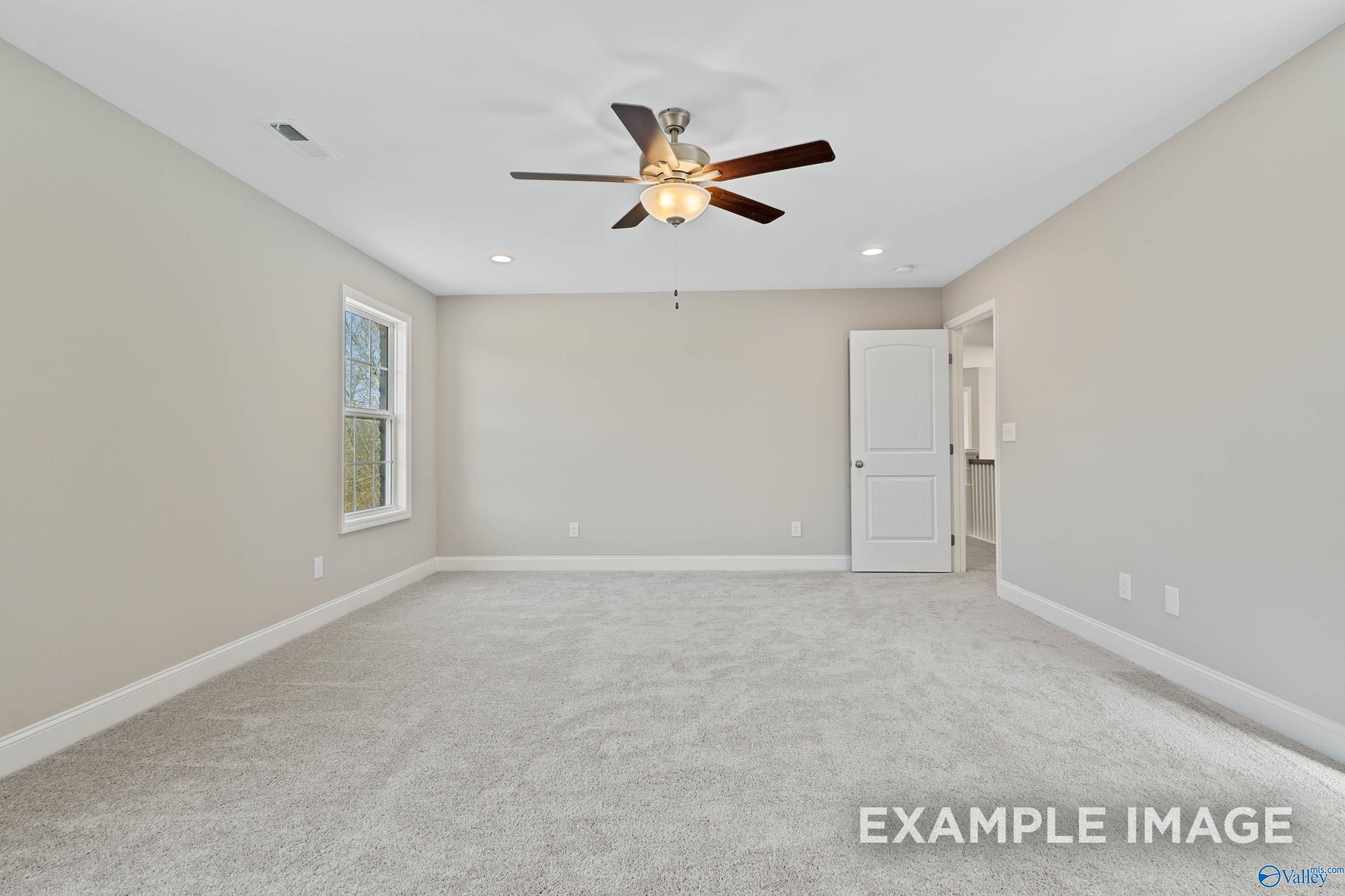 Spacious carpeted bedroom with ceiling fan in The Madison D floor plan at Evergreen Mill in Madison, Alabama.