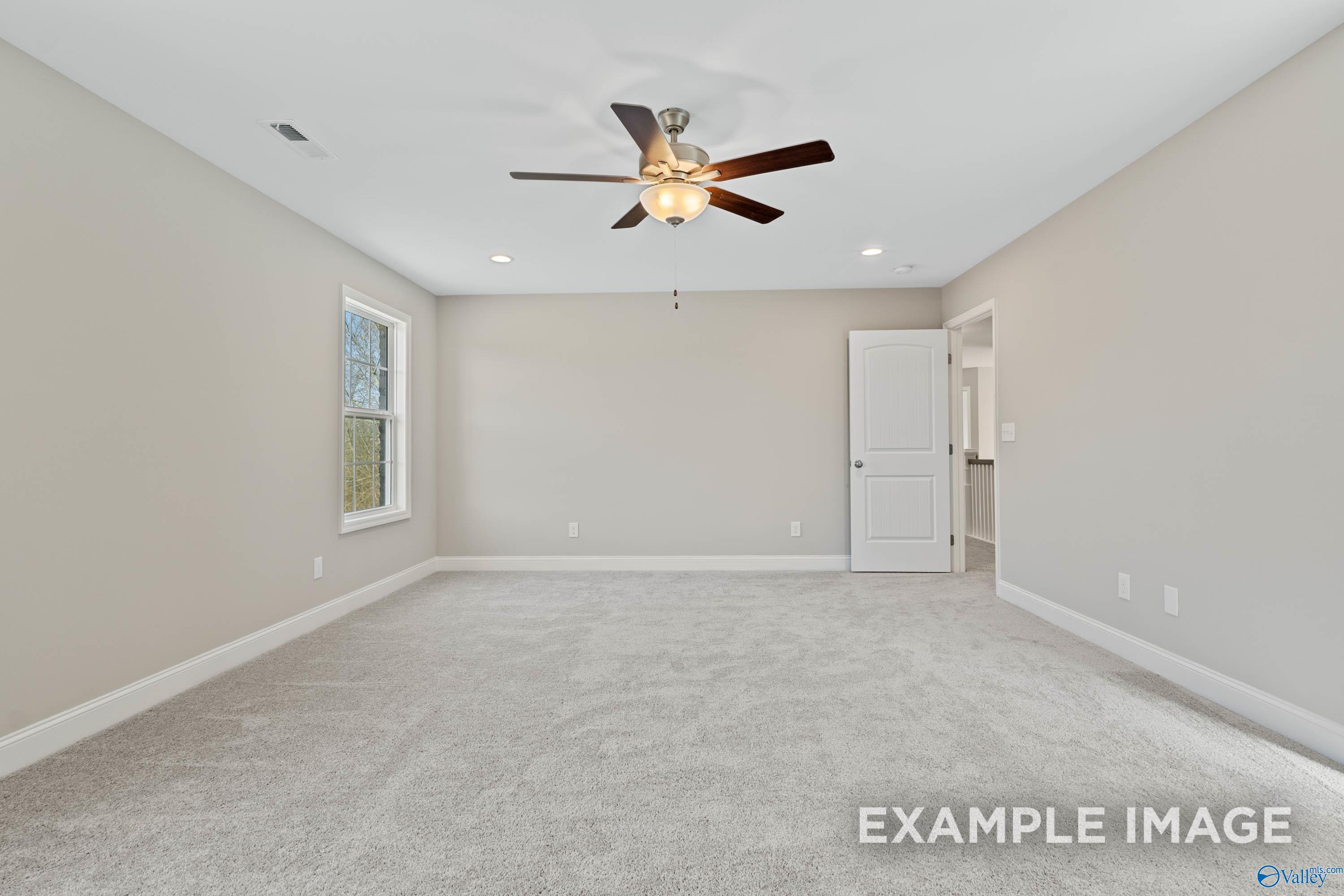 Spacious carpeted bedroom with ceiling fan in The Madison D floor plan at Evergreen Mill in Madison, Alabama.