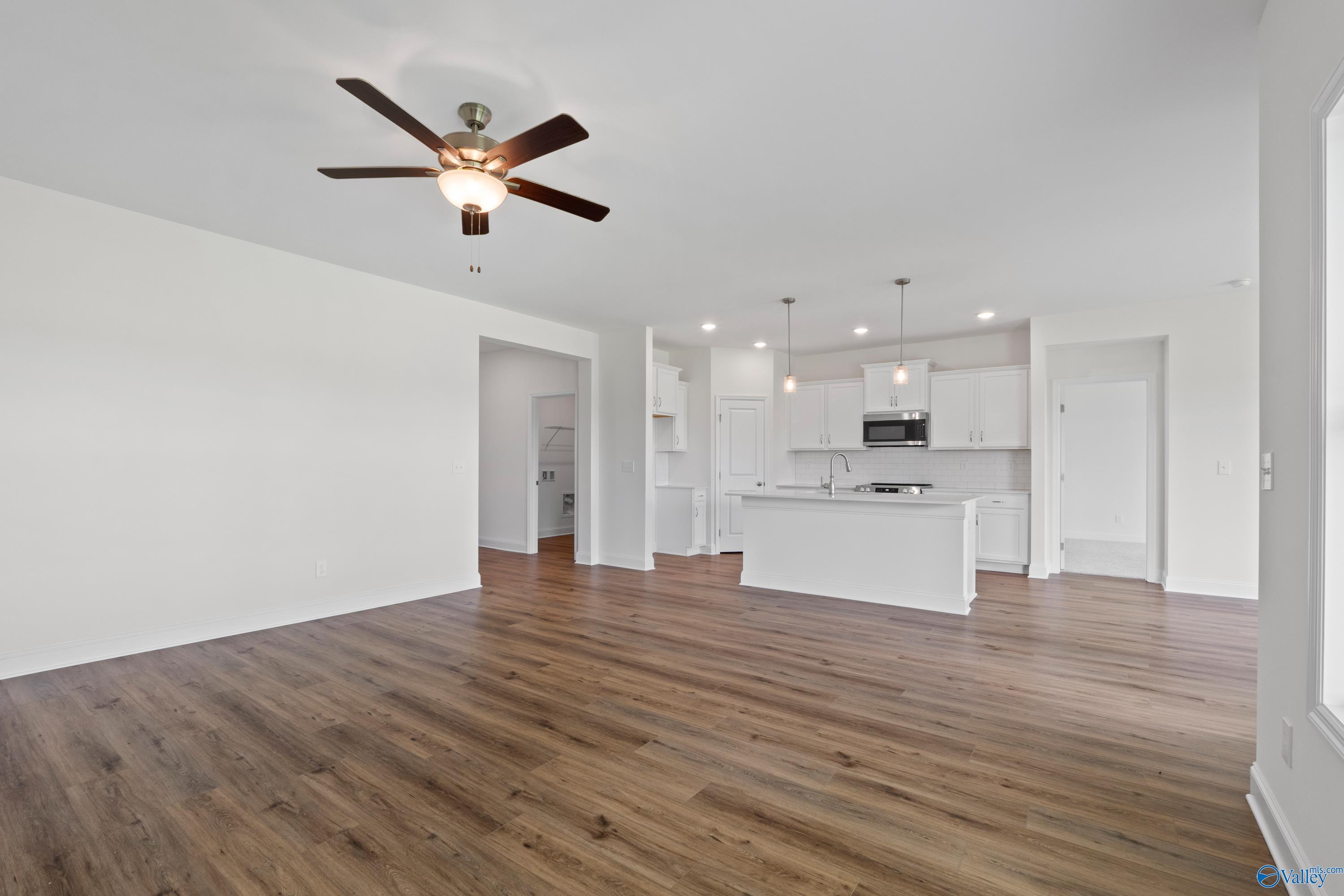Open-concept living room and kitchen with white cabinets in The Everett B floor plan, The Meadows, Athens, Alabama.