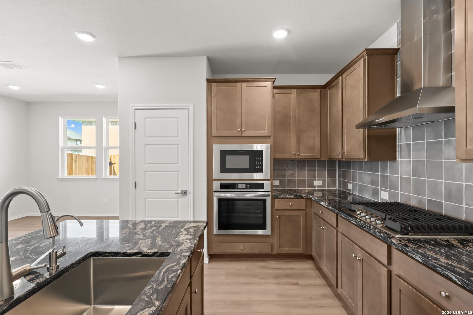 Modern kitchen with granite countertops, stainless appliances, and wood cabinets in Davidson Homes The Daphne I, Bricewood, San Antonio