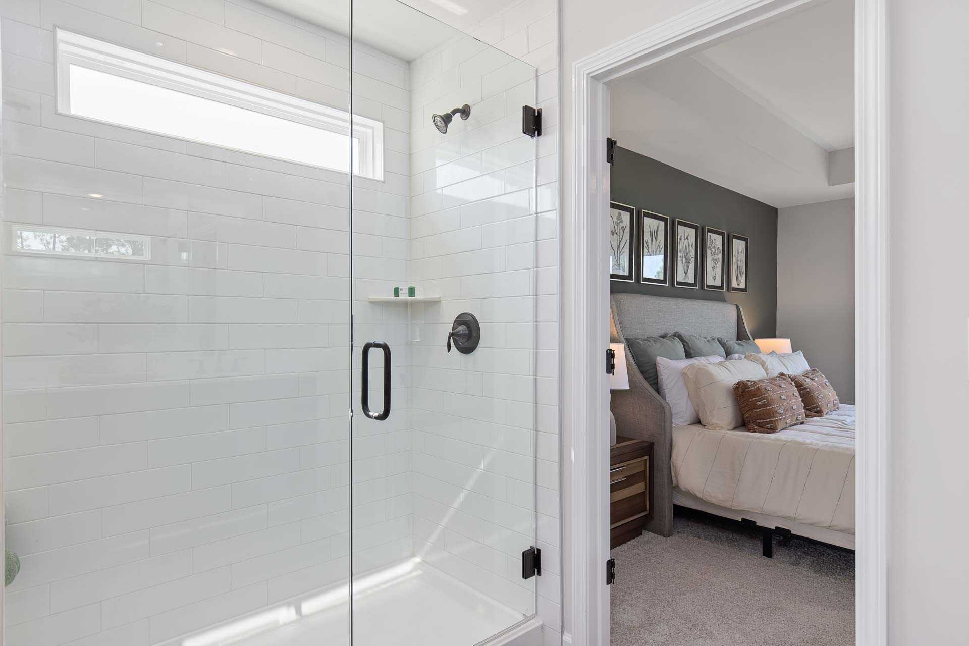 Modern master bathroom with frameless glass shower and adjacent bedroom at Sierra Heights in Clayton, North Carolina